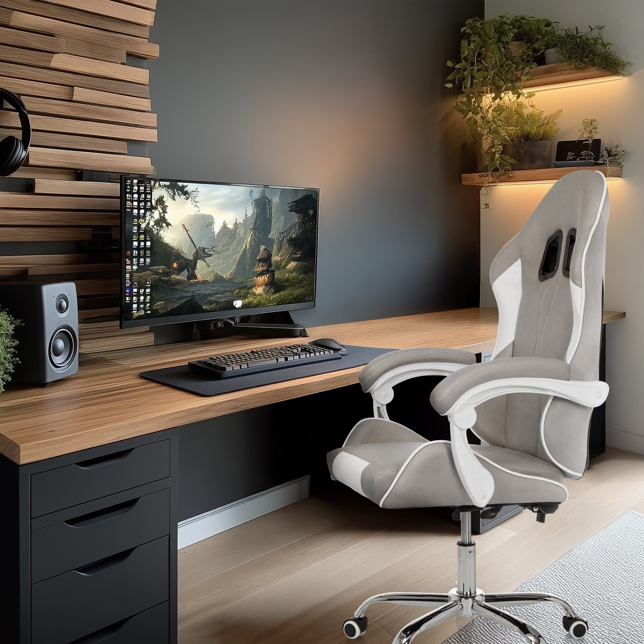 Ein moderner Schreibtisch mit Computer, Tastatur, Lautsprecher und grauem Gaming-Stuhl. Topfpflanzen auf Holzböden.