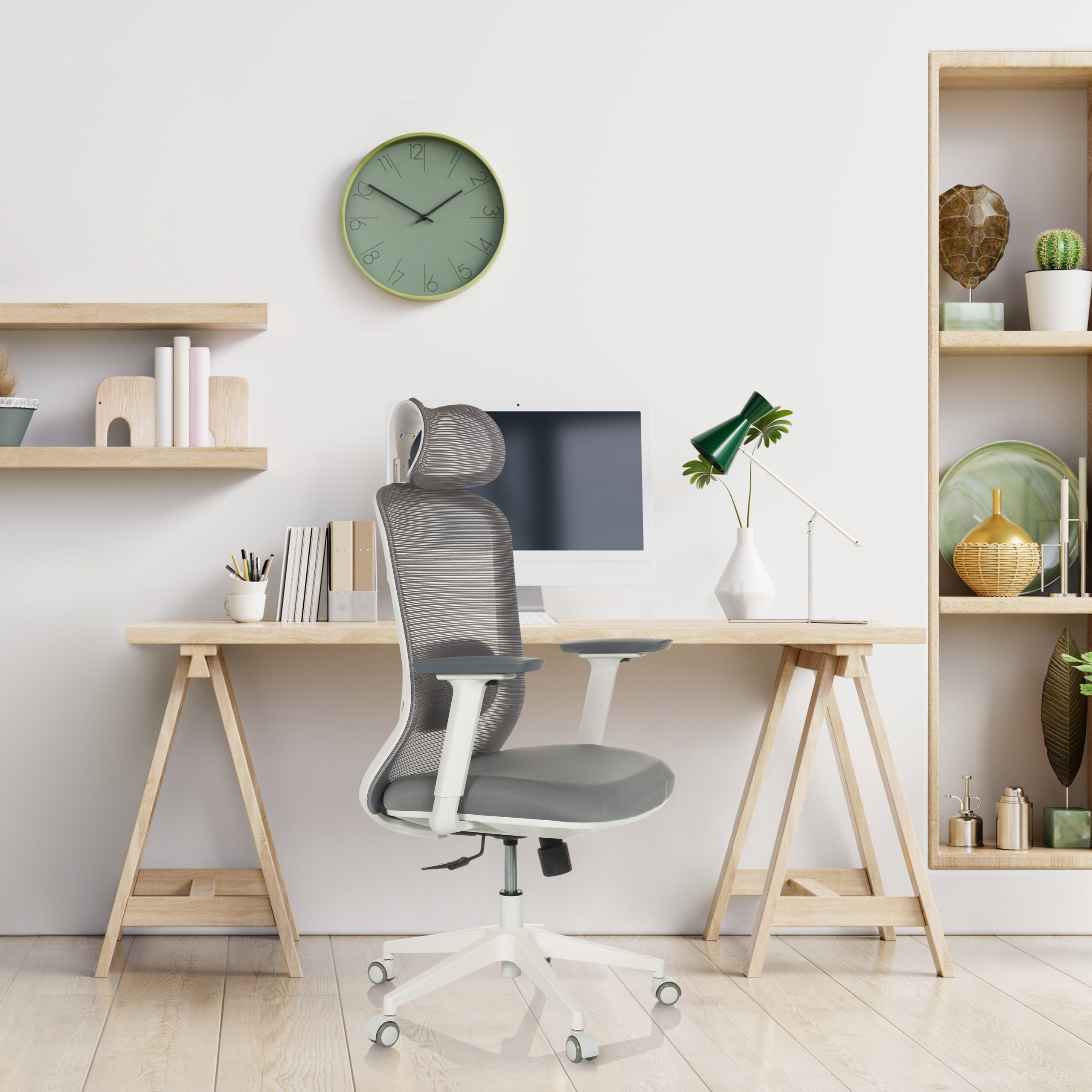 Moderne Schreibtisch mit einem grauen Bürostuhl, Computer, Lampe, grüner Wanduhr und Regalen mit Dekoration.