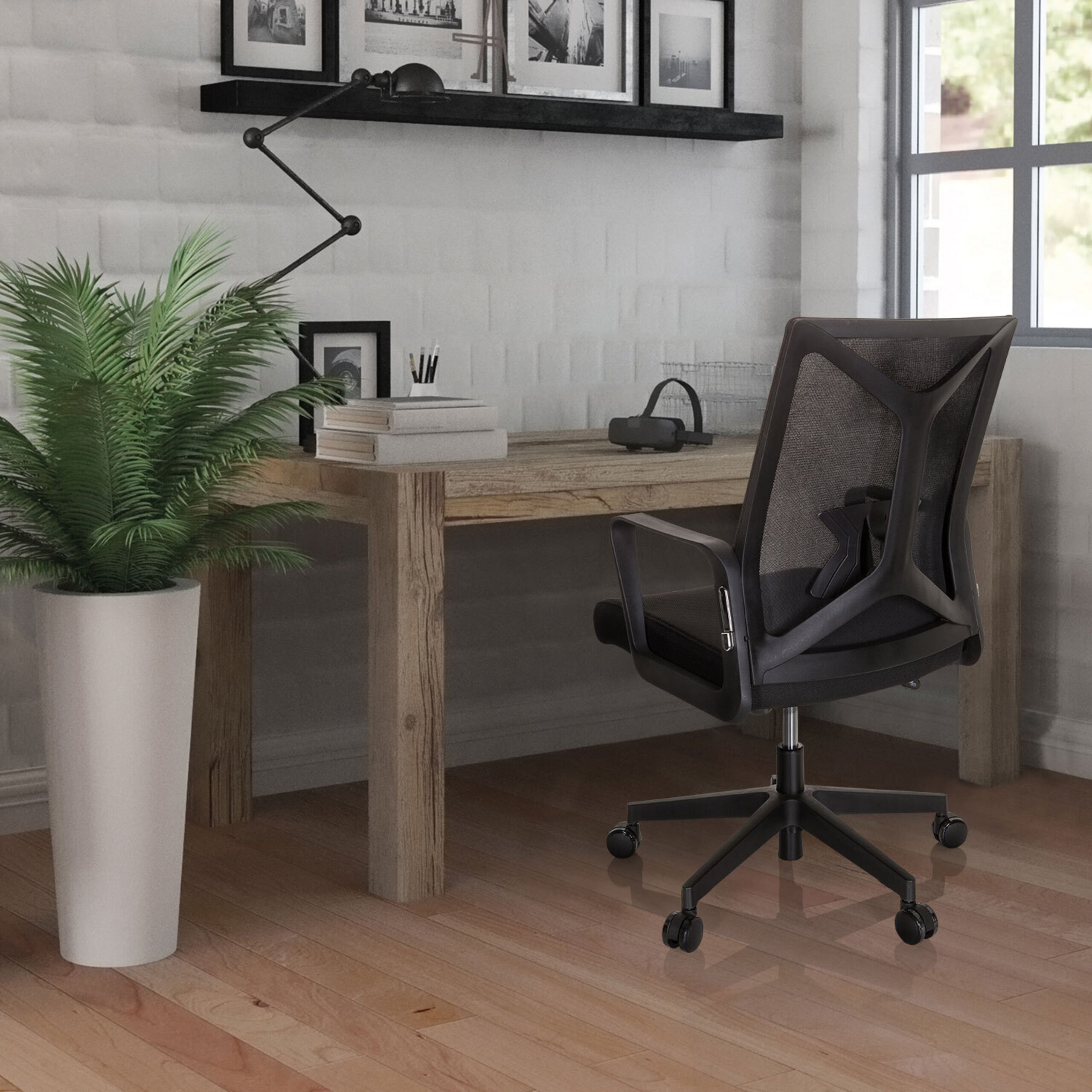 Moderne Büroeinrichtung mit Holztisch, schwarzem Drehstuhl, großer Pflanze im weißen Topf und weißer Backsteinwand.