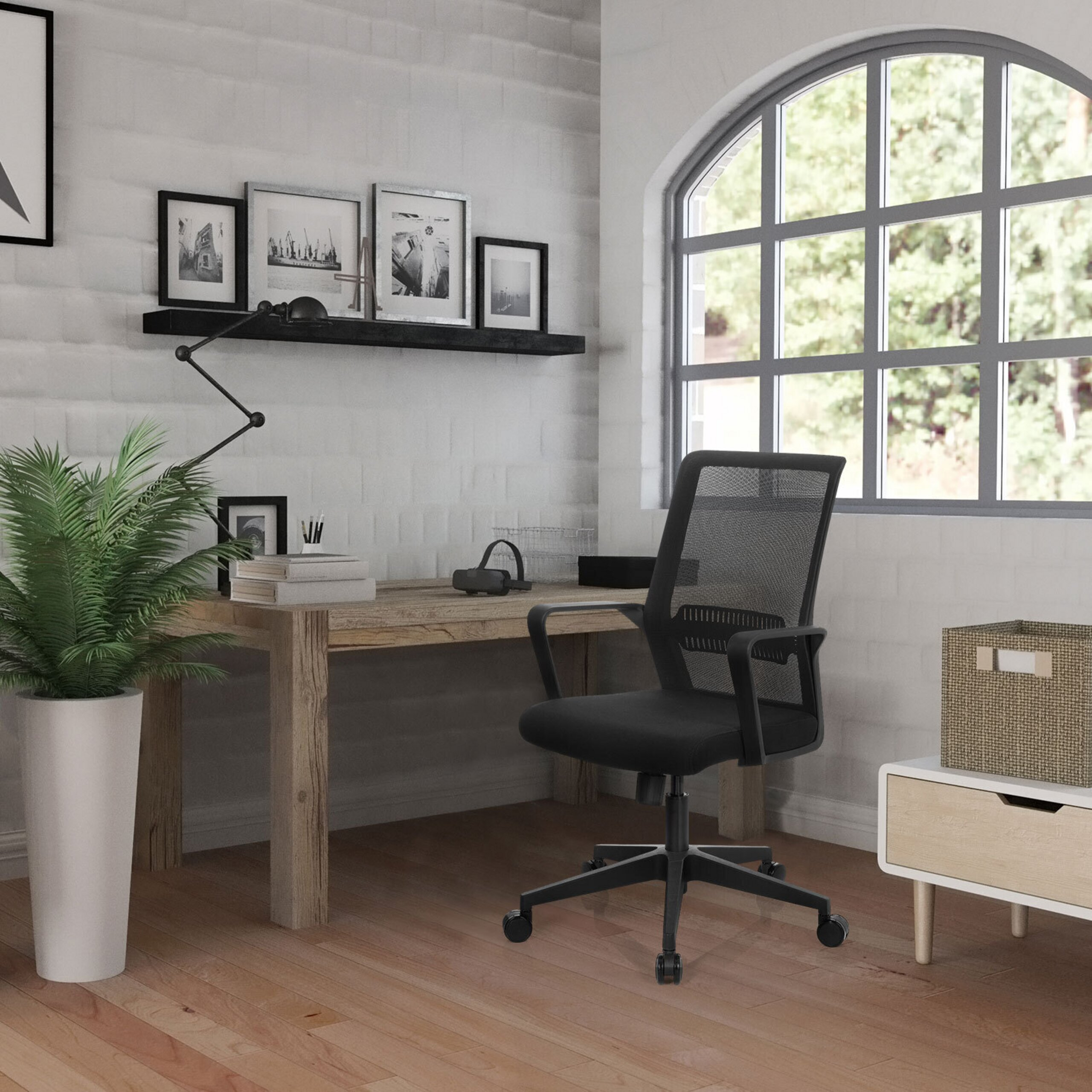 Moderne Heimarbeitsecke mit Schreibtisch, schwarzem Buerostuhl und einem Regal an der weissen Backsteinwand.
