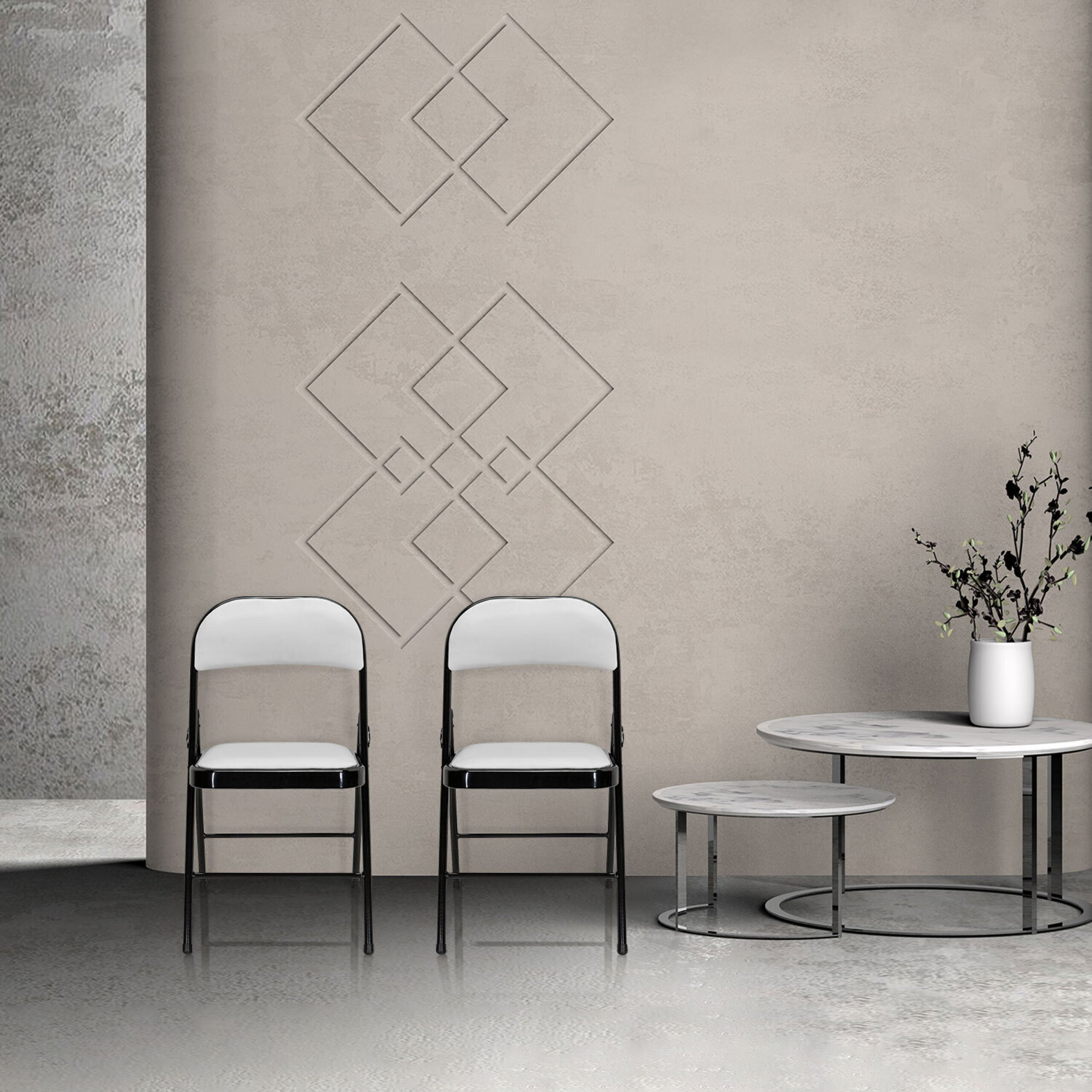 Zwei schwarz-weiße Stühle stehen an einer beige Wand mit geometrischen Mustern neben zwei runden Tischen.