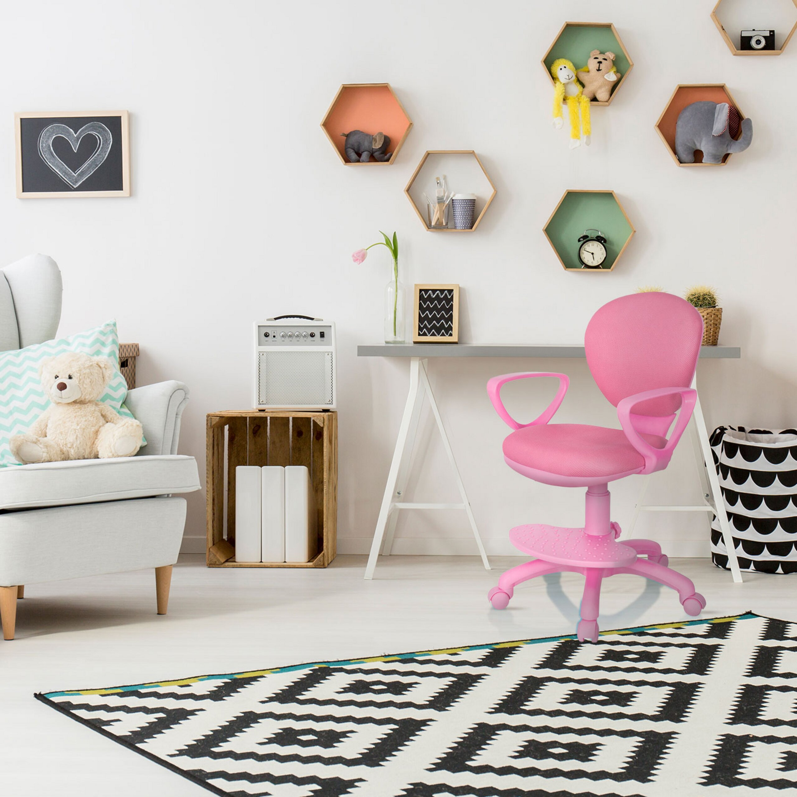 Helles Kinderzimmer mit rosa Schreibtischstuhl, hellblauem Sessel mit Teddybär, geometrischem Teppich und Wandregalen.