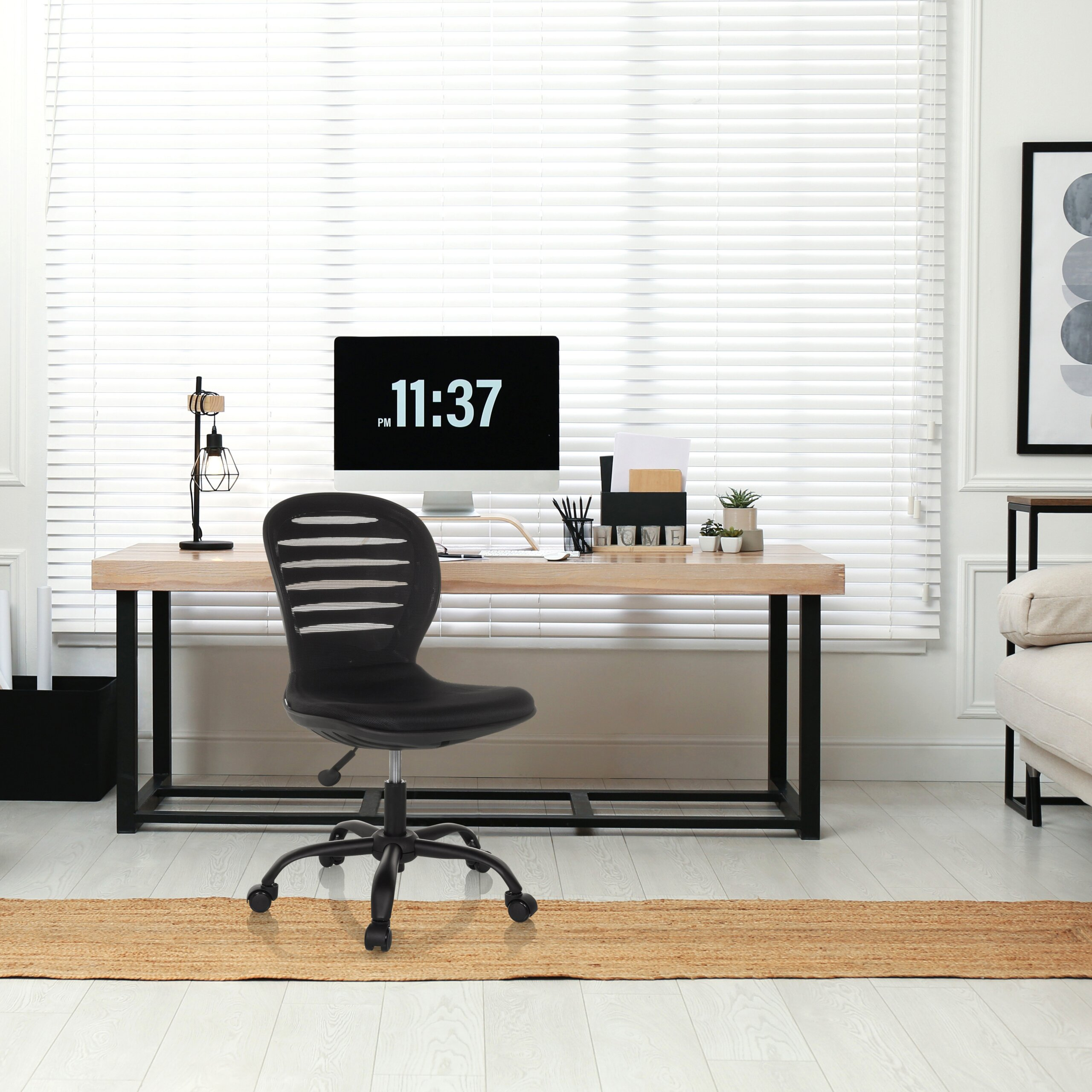 Ein modernes Arbeitszimmer mit schwarzem Rollstuhl, Holzschreibtisch, Computer, Lampe und Jalousien.