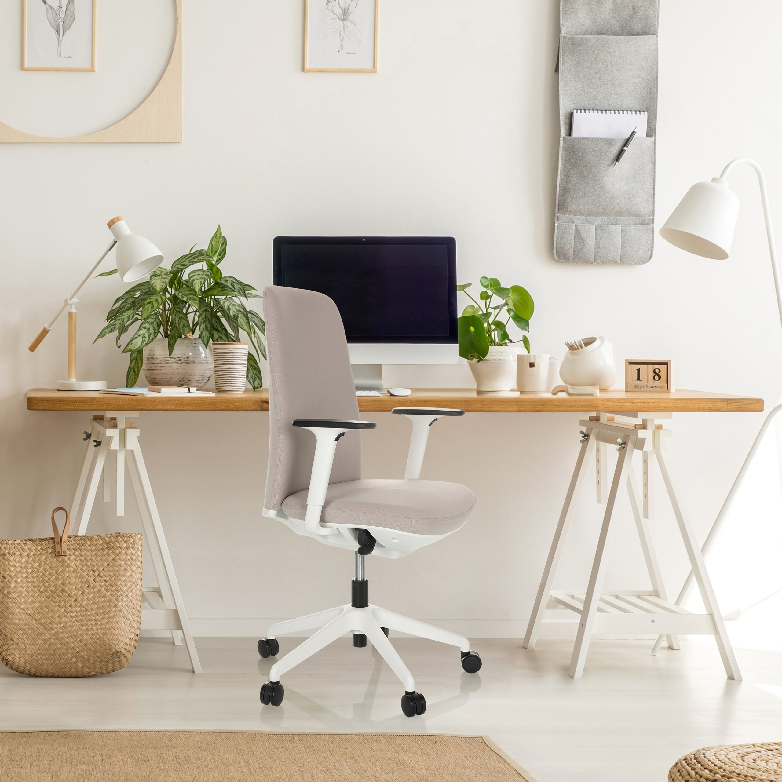 Moderne Schreibtisch-Set mit hellem Holz, einem ergonomischen grauen Stuhl, Pflanzen und einem Computer.