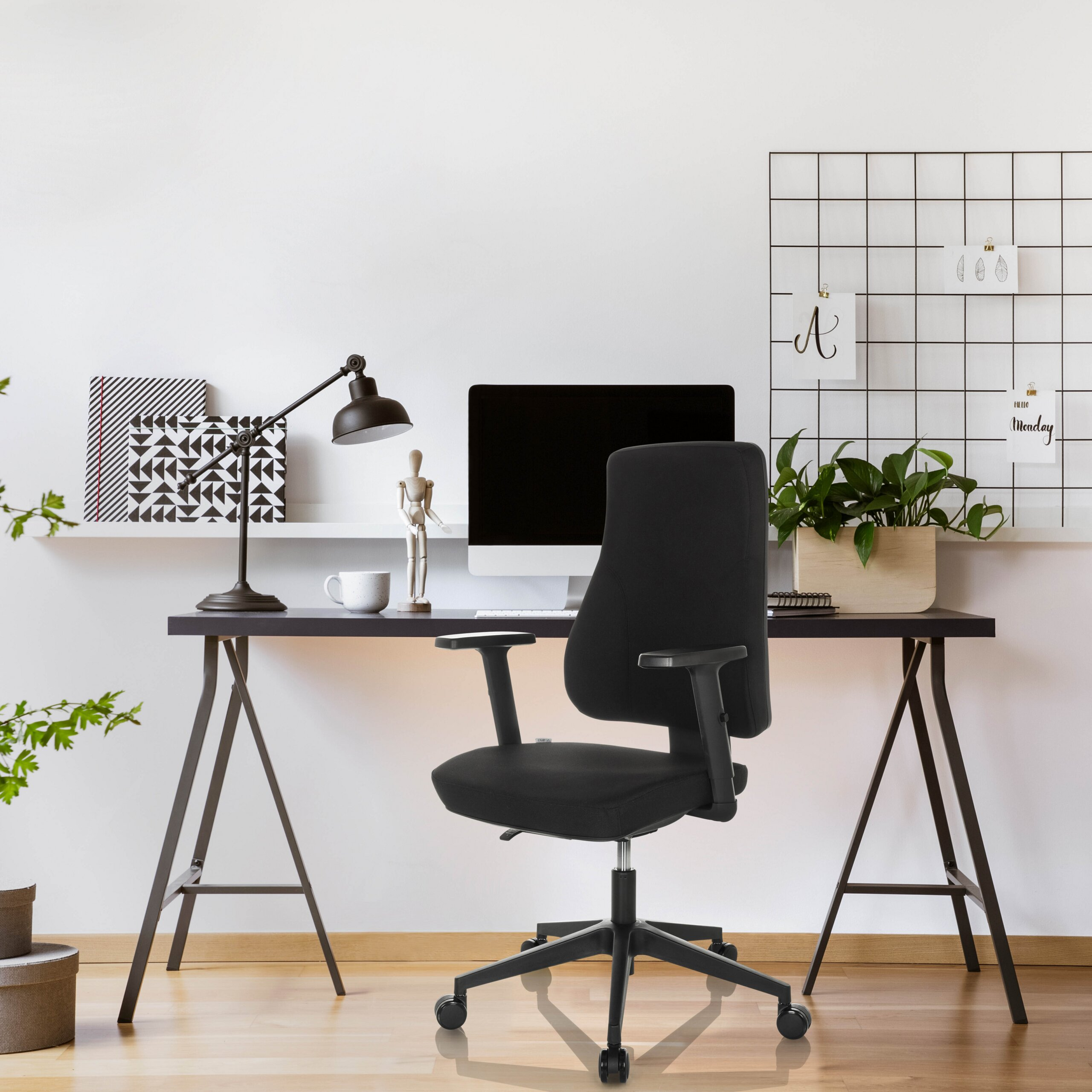 Moderne Schreibtisch mit schwarzem Bürostuhl, Computer, Lampe und Notizen an der weißen Wand.