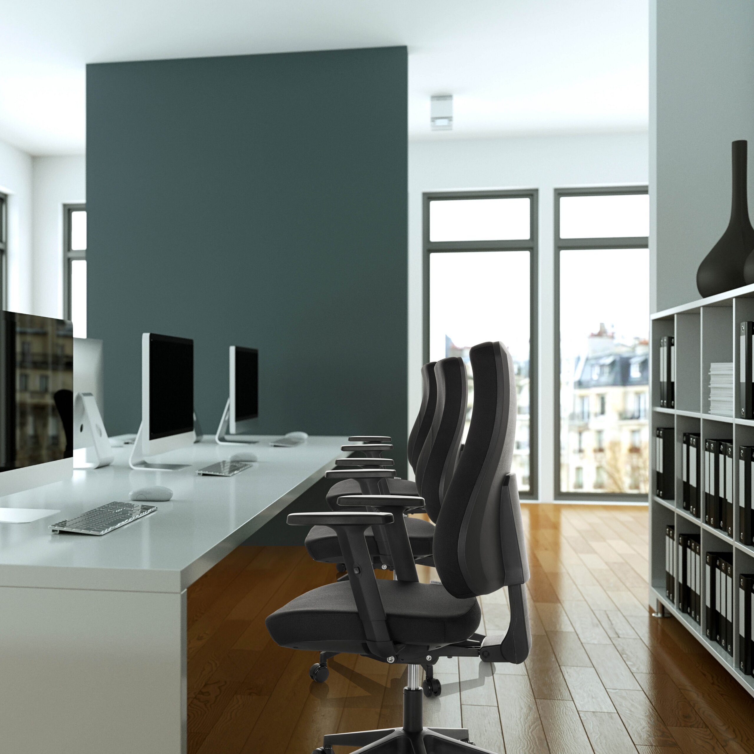 Moderne Büroeinrichtung mit grauen Stühlen, weißen Tischen, Computern und einem Regal mit Ordnern.