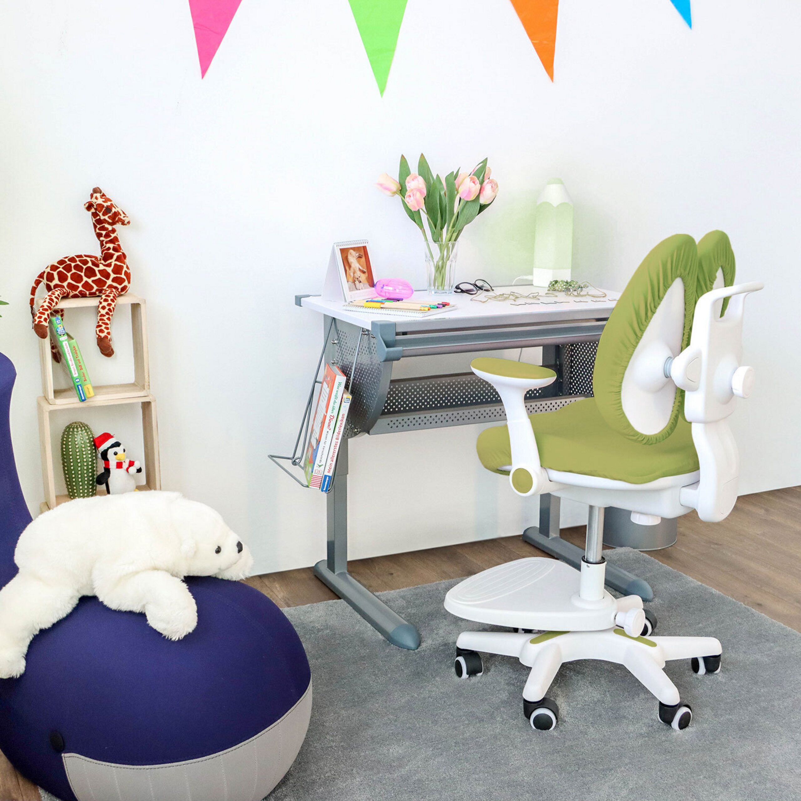 Ein Kinderschreibtisch, ein grüner ergonomischer Stuhl und Spielzeug in einem hellen Raum.