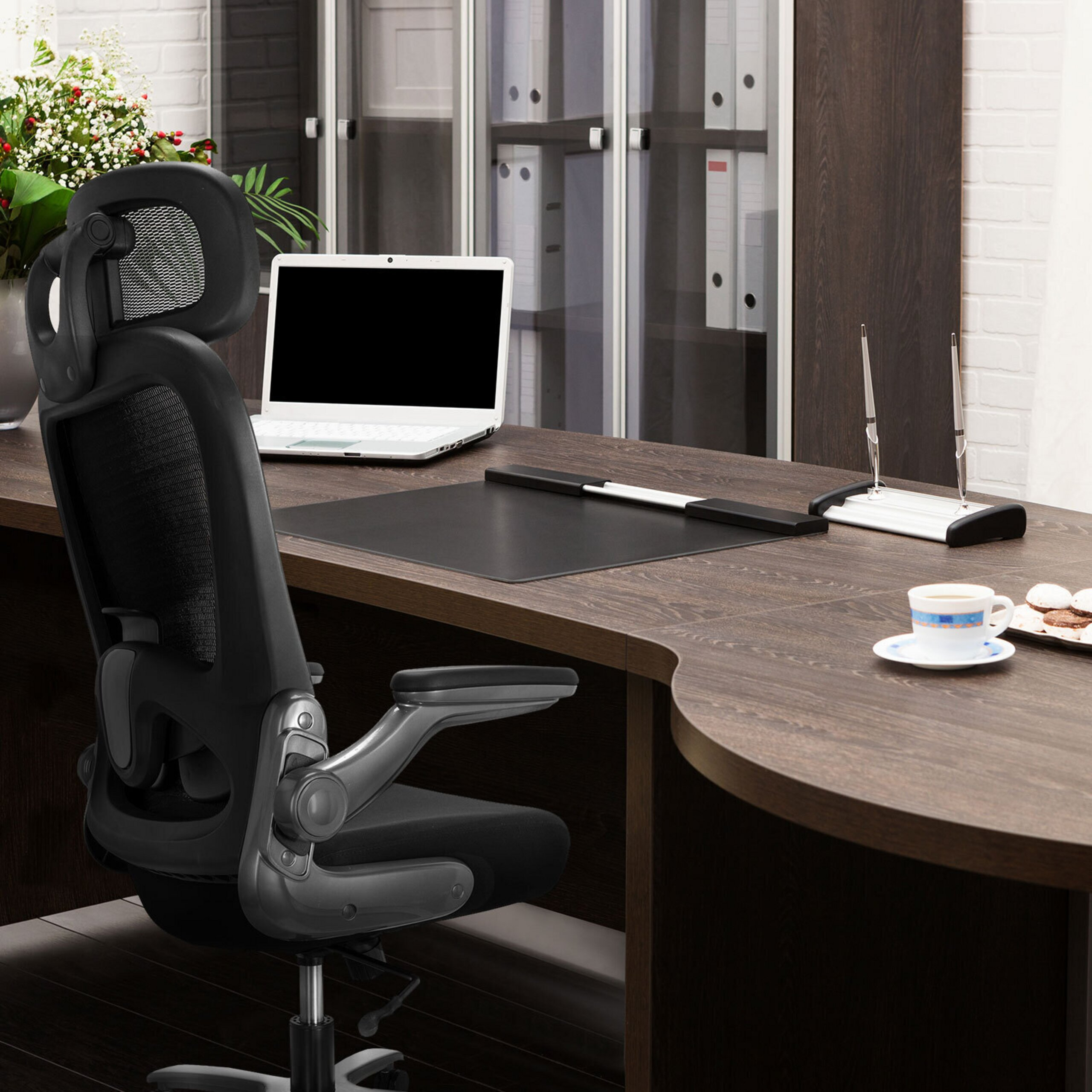 Moderne Büroeinrichtung mit Laptop, Stuhl und Kaffeetasse auf dunklem Schreibtisch.