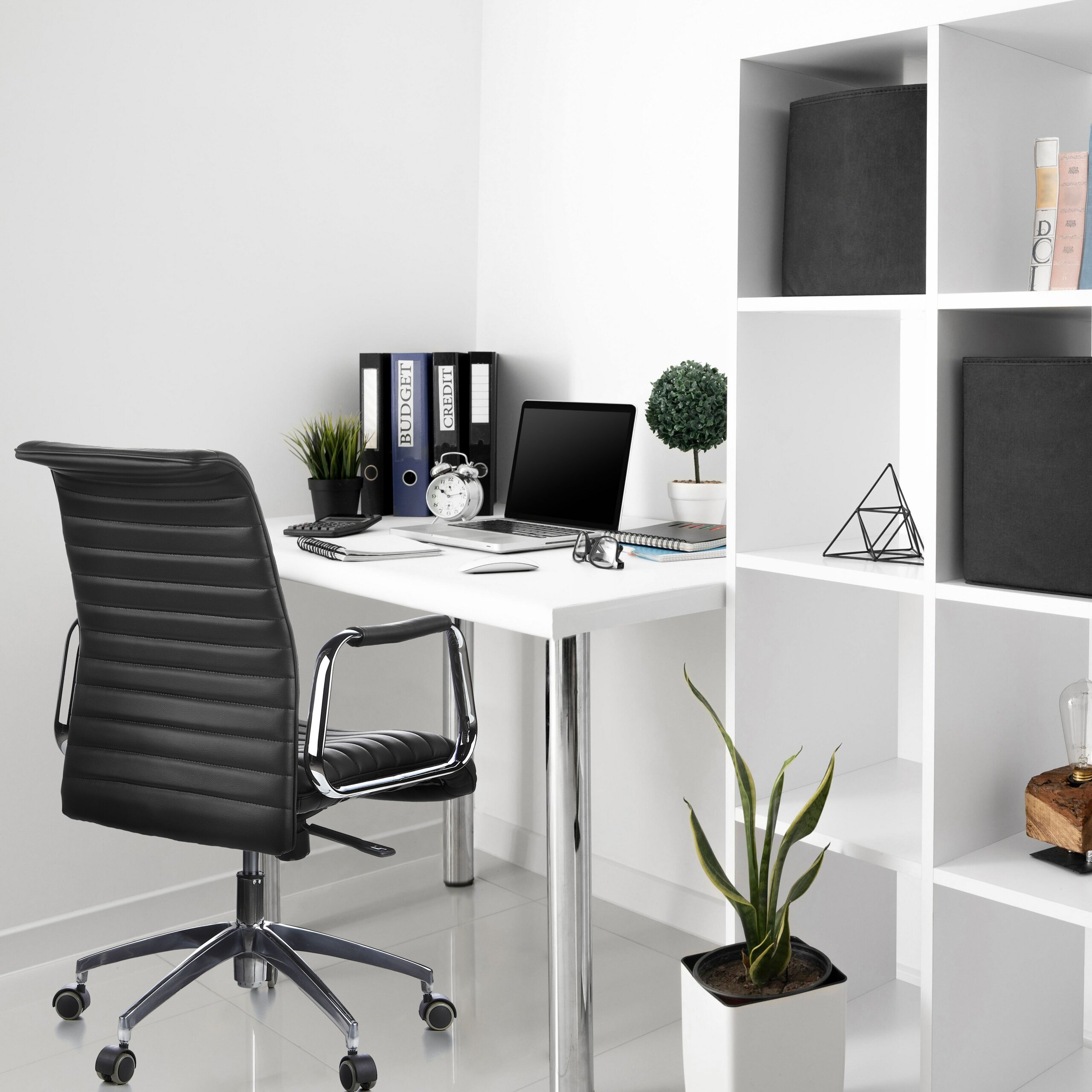 Moderne weiße Arbeitsstation mit schwarzem Stuhl und Laptop.