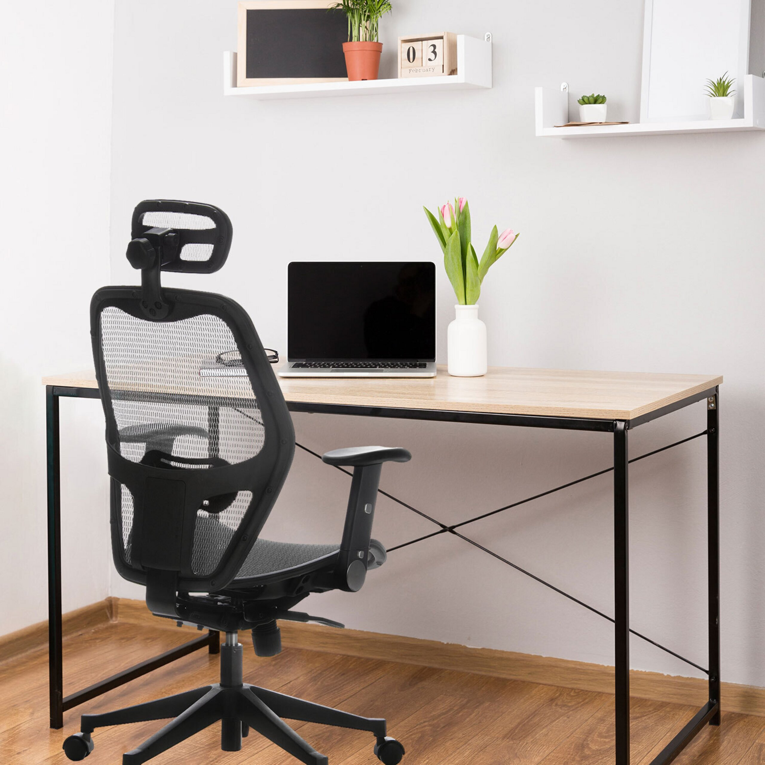 Ein moderner Schreibtisch mit Laptop und Blumen, davor ein schwarzer Bürostuhl.