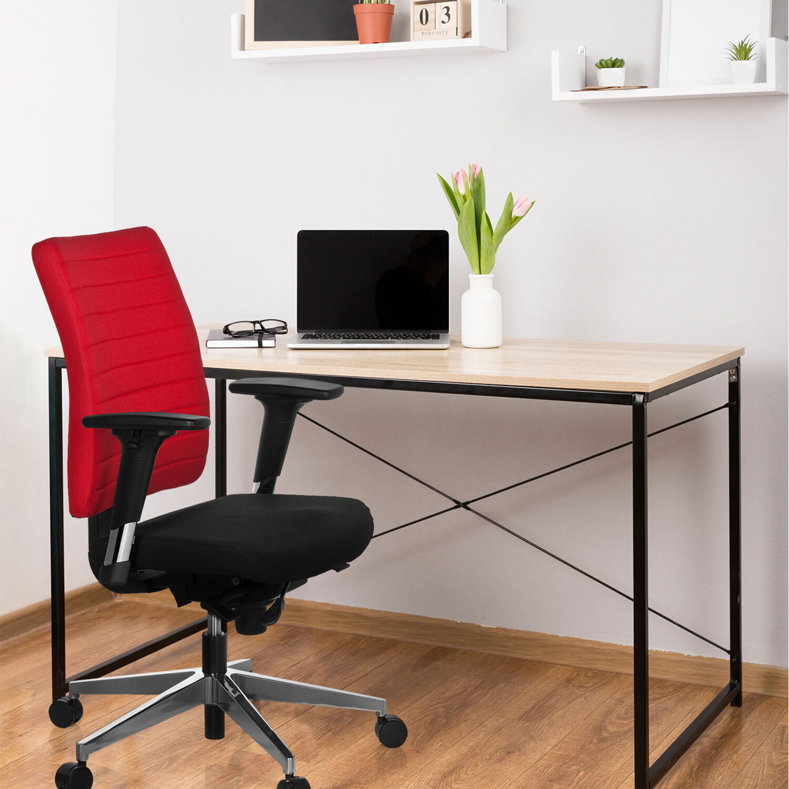 Büro mit Holztisch, schwarzem und rotem Bürostuhl, Laptop und Blumen.