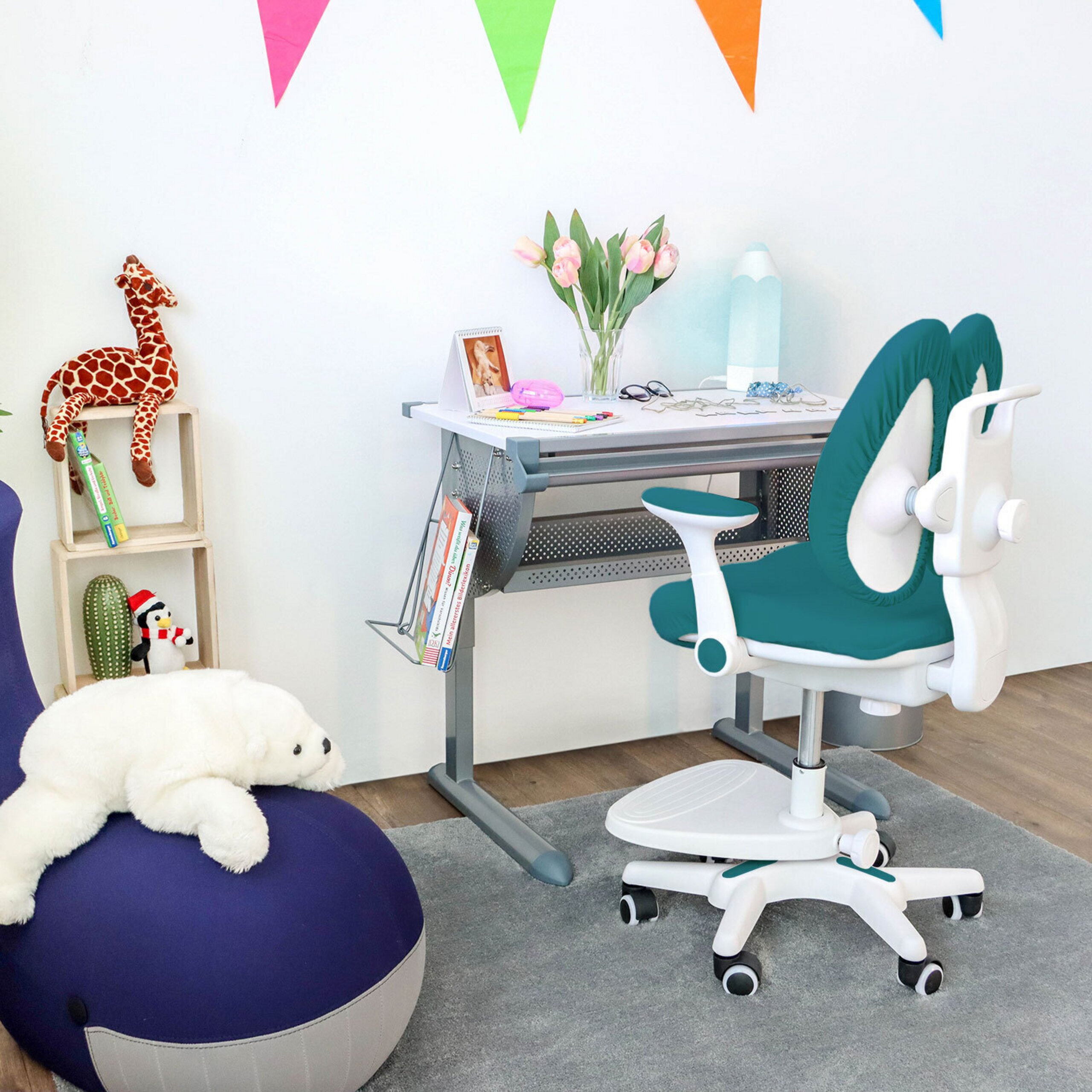 Ein Kinderzimmer mit Schreibtisch, grünem Stuhl, bunten Girlanden und Stofftieren.