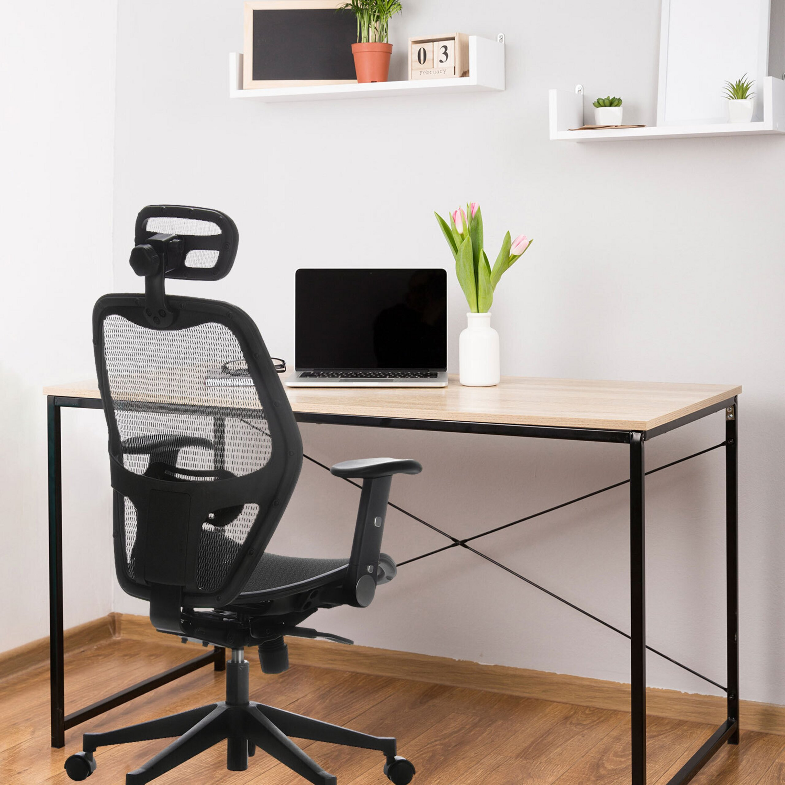Ein Home-Office mit Schreibtisch, schwarzem Bürostuhl, Laptop, Blumen und Regalen an der Wand.