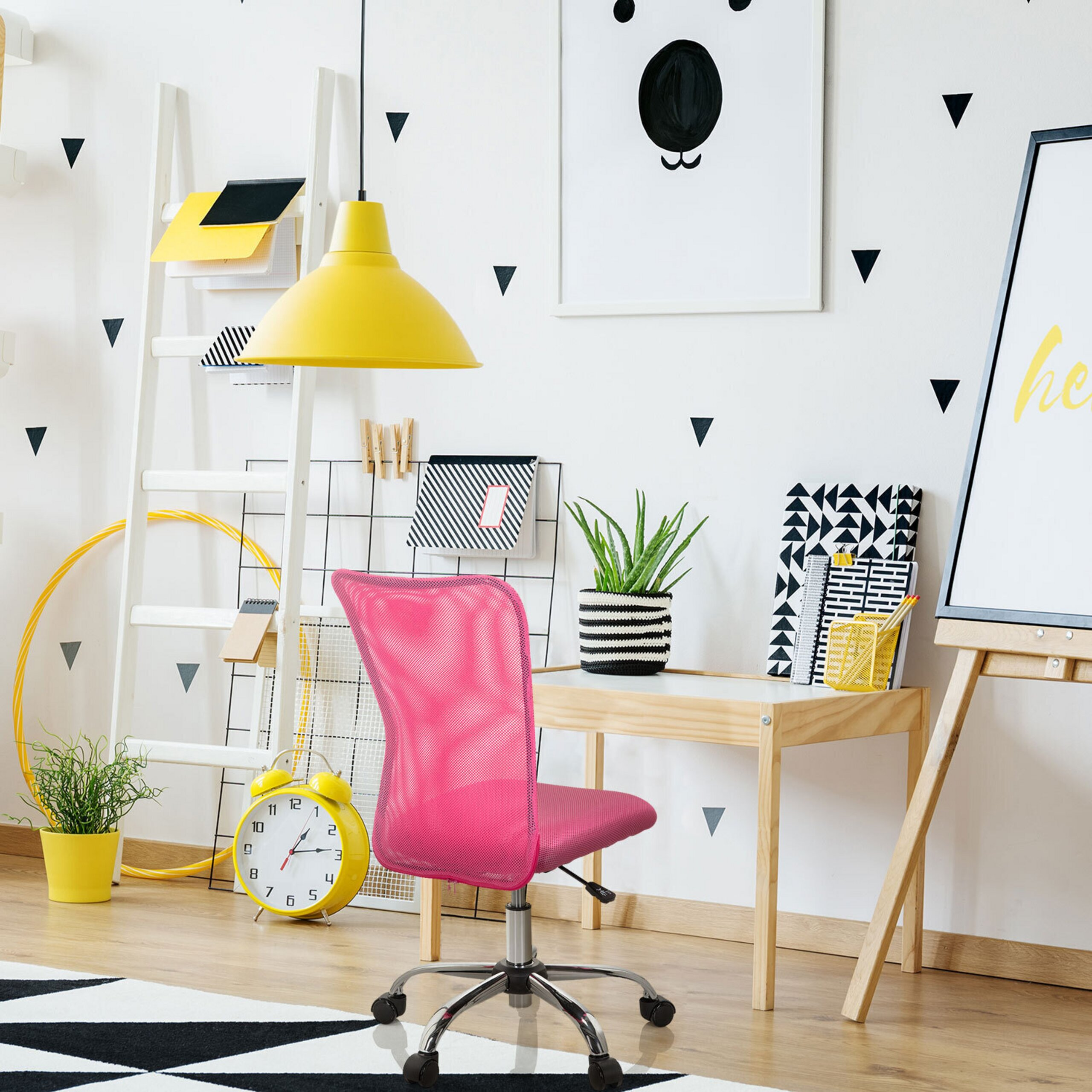 Einhelliger Arbeitsplatz mit rosa Stuhl, Holztisch, gelber Lampe und dreieckigen Aufklebern an der Wand.