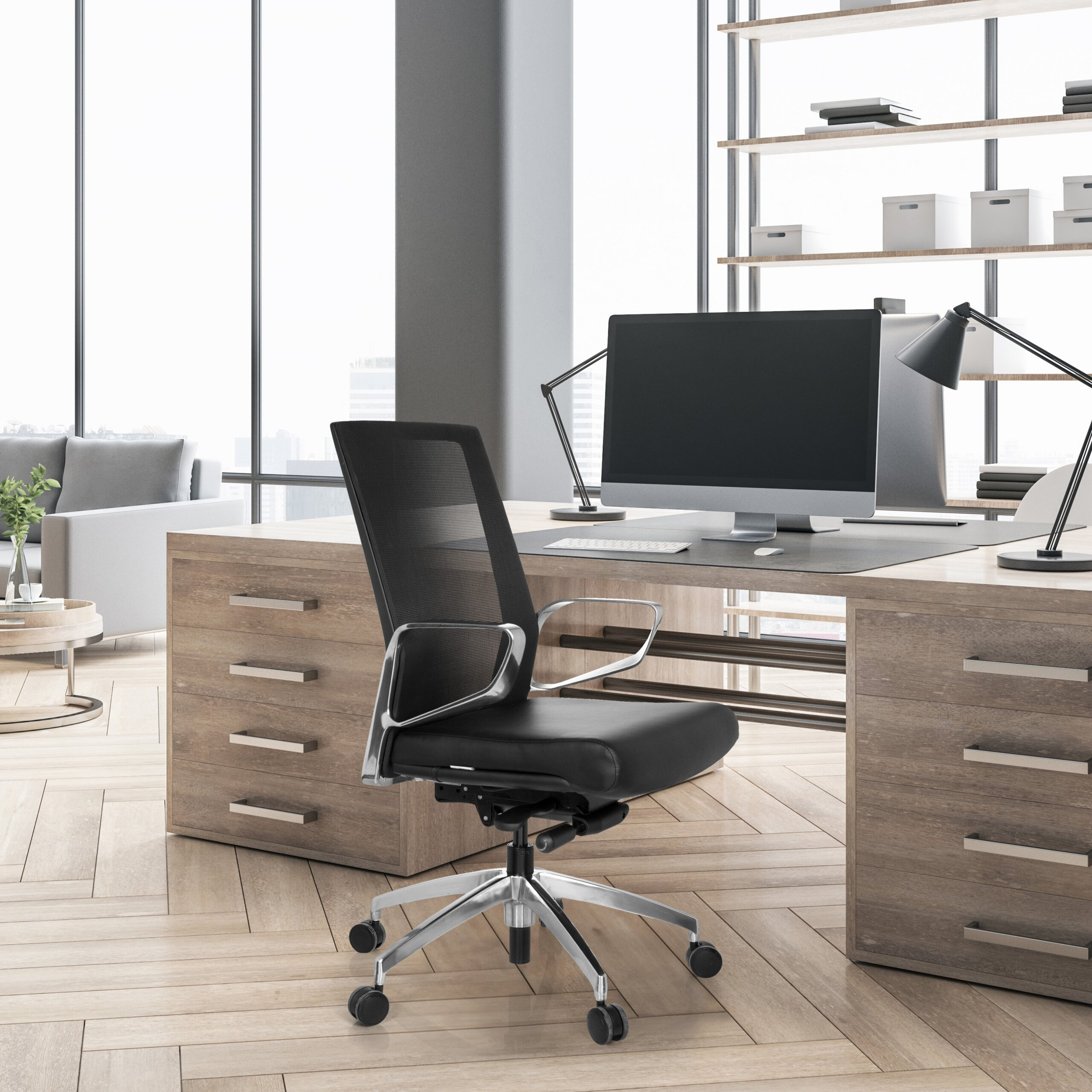 Büro mit Holztisch, schwarzem Drehstuhl und PC vor großem Fenster mit heller Couch im Hintergrund.