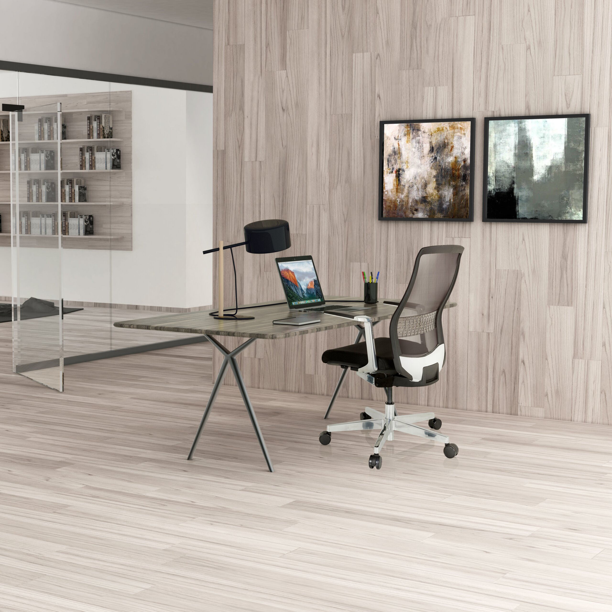 Holztisch mit Laptop und Lampe, ein ergonomischer Bürostuhl davor, Holzwand mit zwei abstrakten Gemälden im Hintergrund.