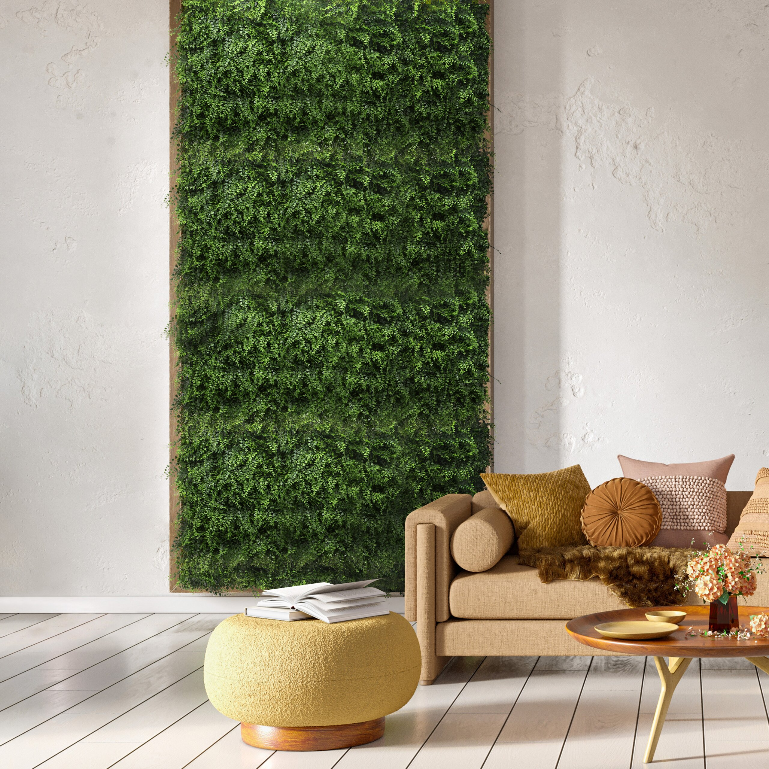 Ein Wohnzimmer mit einer großen grünen Pflanzenwand, einem beigen Sofa und einem gelben runden Hocker auf weißem Boden.