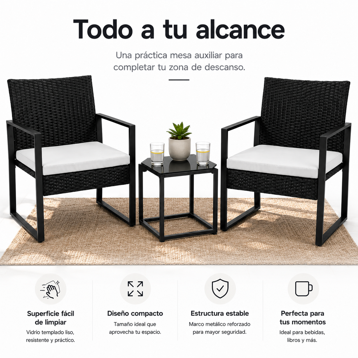 Dos sillones de ratán negro con cojines blancos y una mesita auxiliar con una planta y vasos sobre una alfombra.