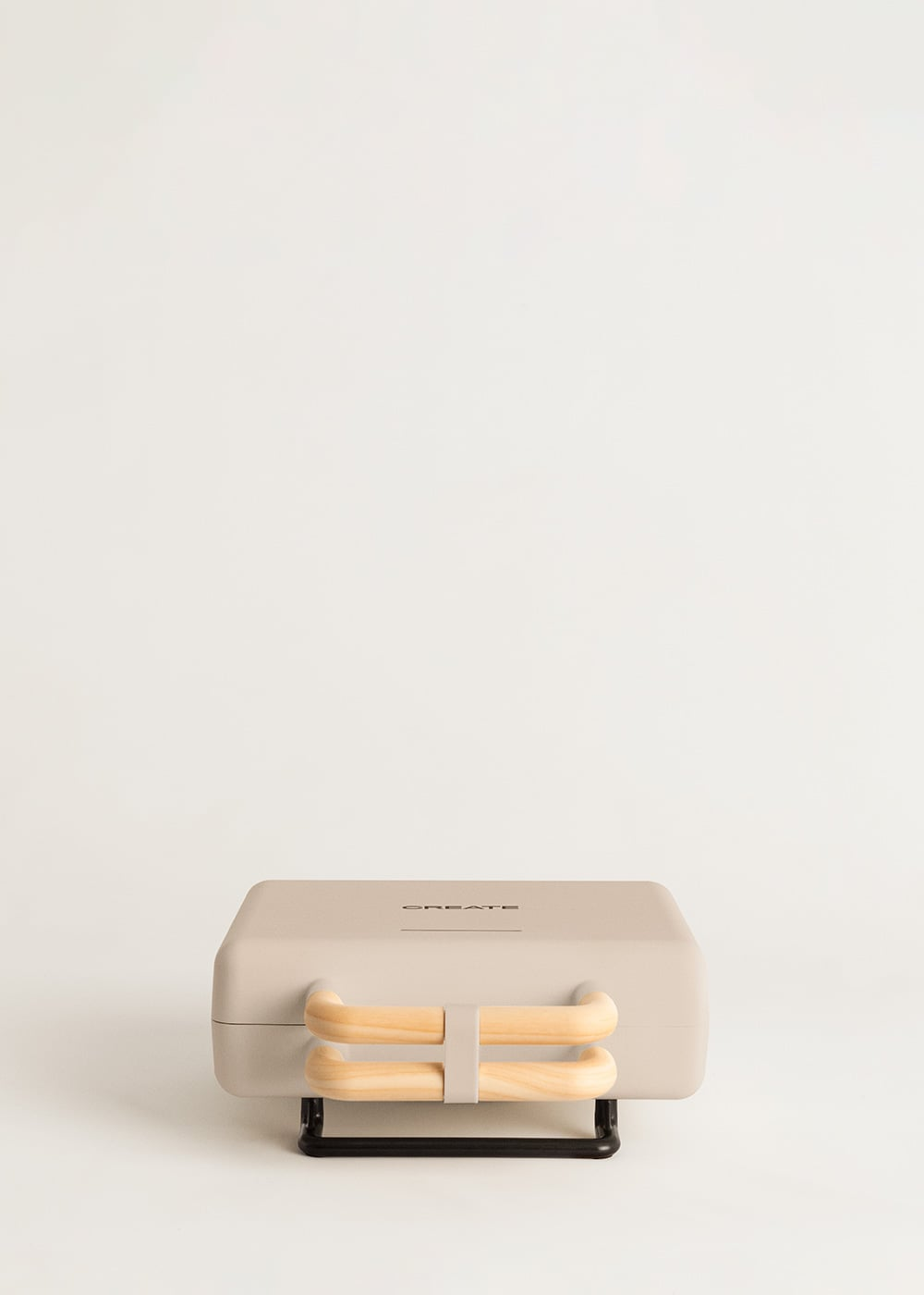 Una sandwichera beige cerrada con asas de madera y base negra, sobre un fondo gris claro.
