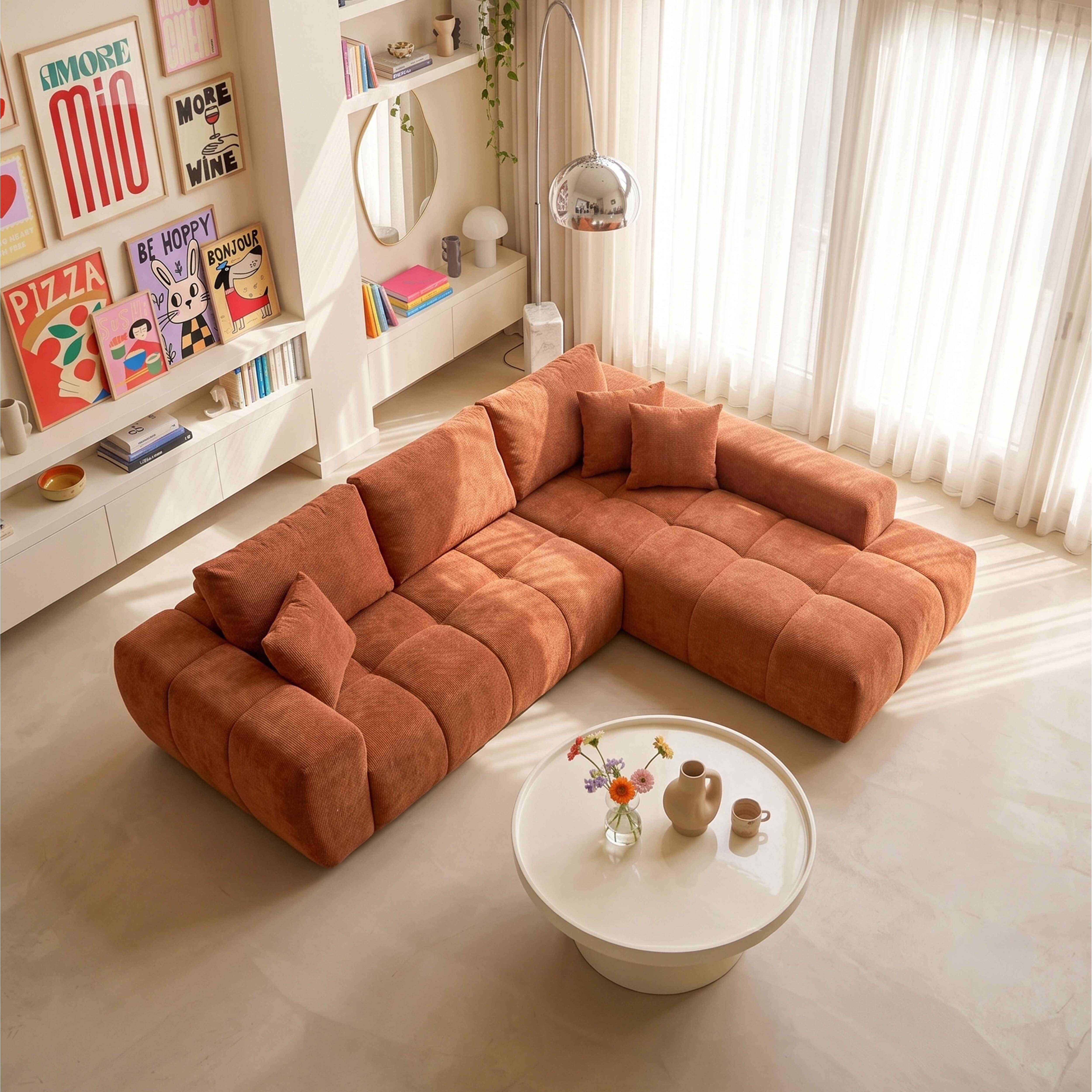 Ein großes, orangefarbenes Ecksofa in einem hellen Wohnzimmer mit Bilderwand und weißem Couchtisch.