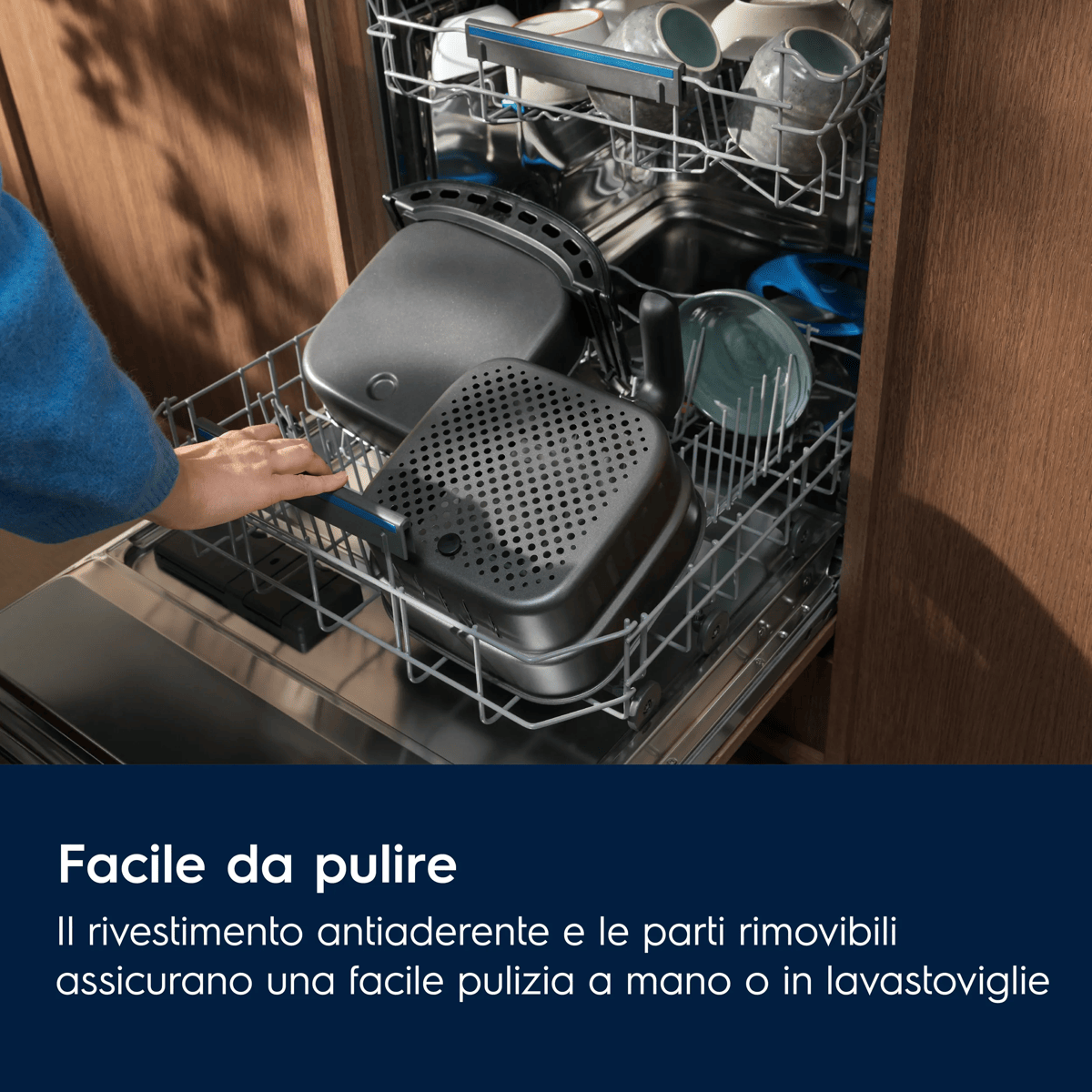 Una persona carica parti di friggitrice nel cestello inferiore di una lavastoviglie aperta.