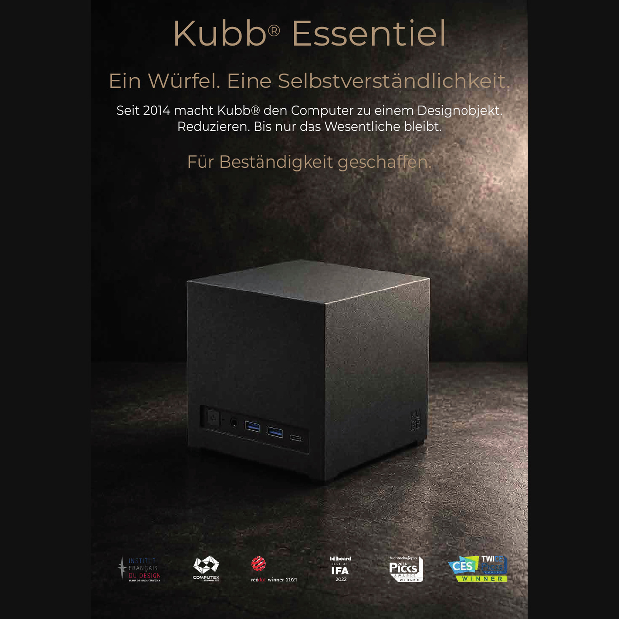 Czarny, sześcianowaty mini PC Kubb Essentiel na ciemnej powierzchni z tekstem i logotypami nagród.