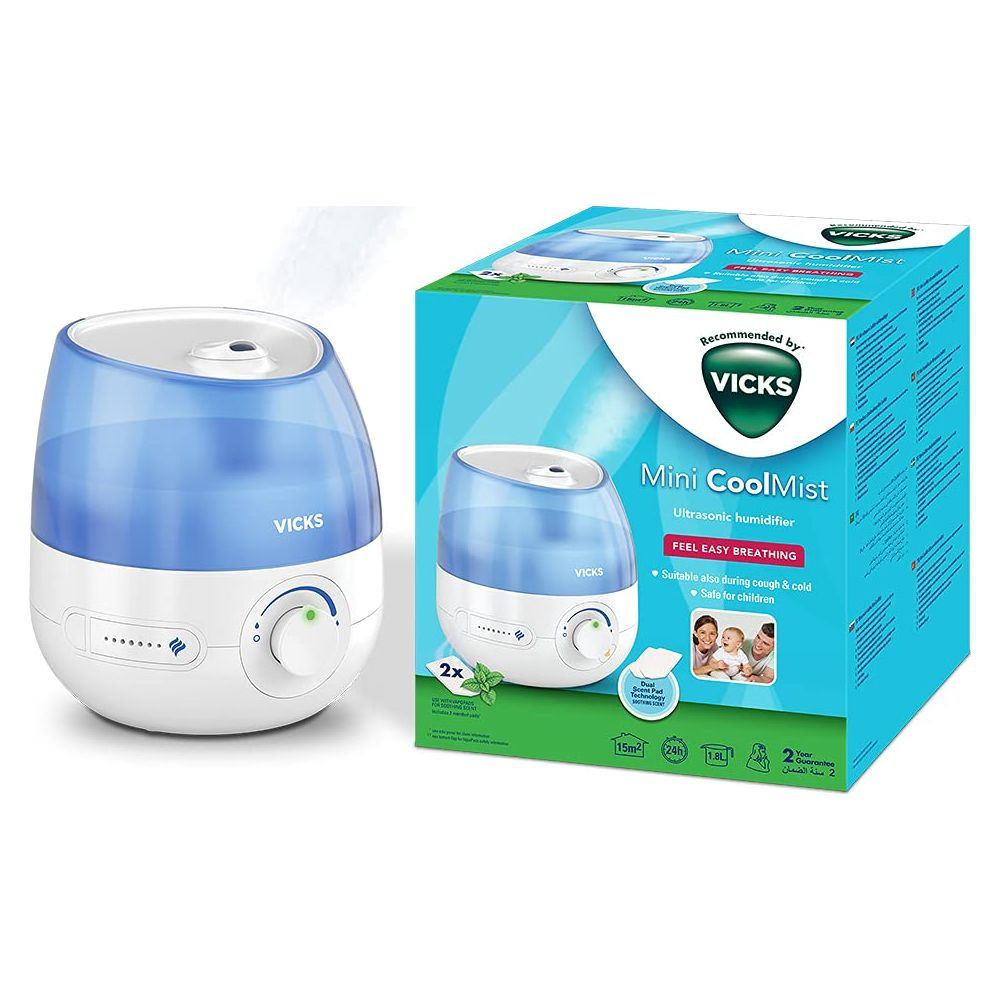 Beyaz arkaplan önünde mavi ve beyaz kutusuyla Vicks Mini CoolMist ultrasonik hava nemlendirici.