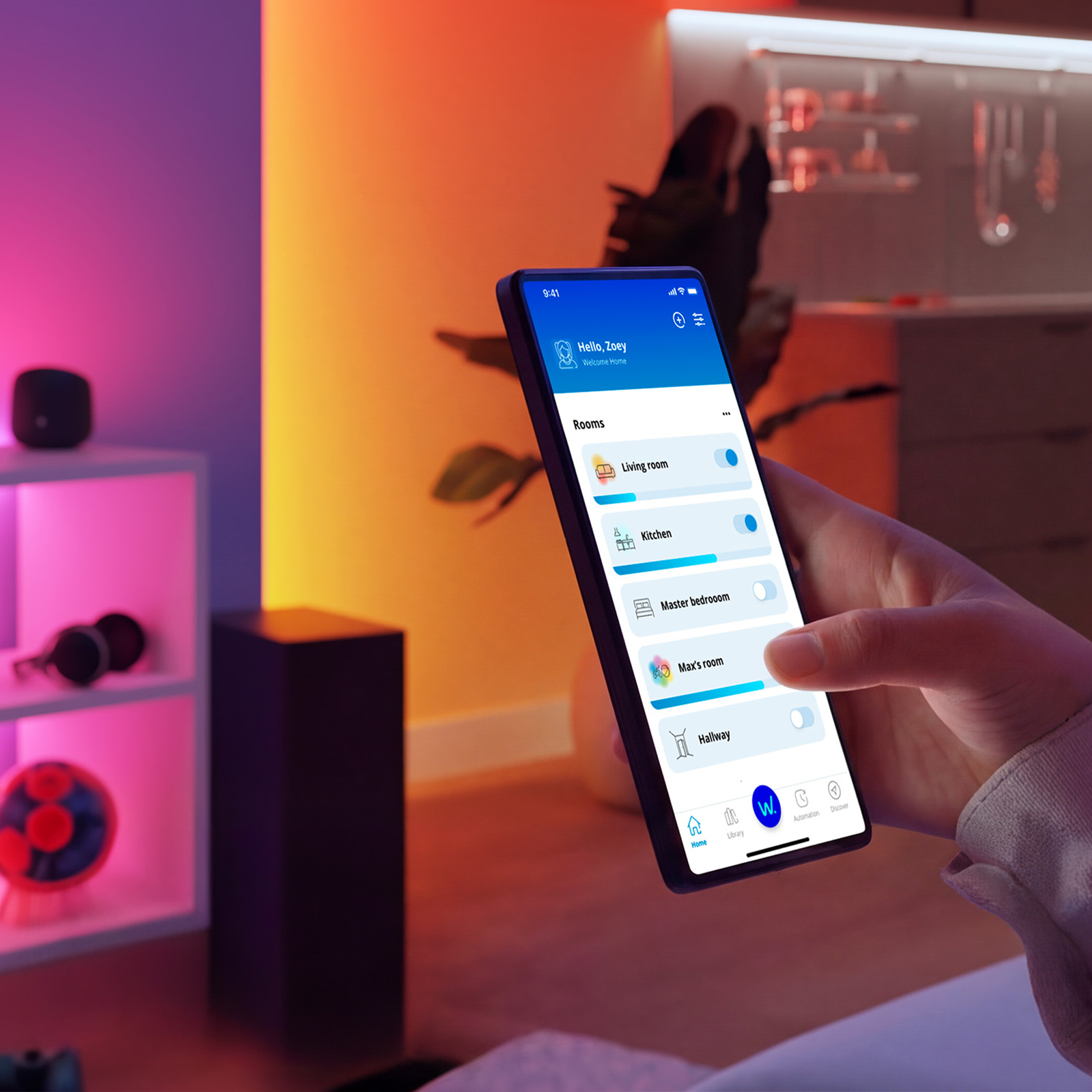 Una persona sostiene un smartphone con una app de hogar inteligente frente a un fondo de habitación colorido.
