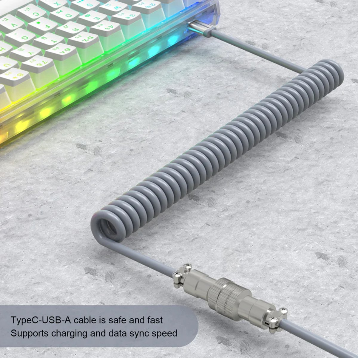 Een grijze spiraalvormige USB-kabel is aangesloten op een verlicht toetsenbord op een grijs oppervlak.