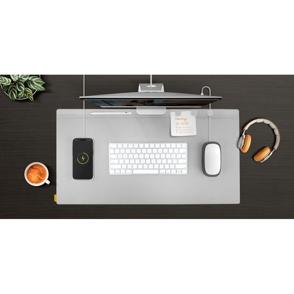 Scrivania ordinata con monitor, tastiera, mouse, telefono in carica, tazza di caffè e cuffie.