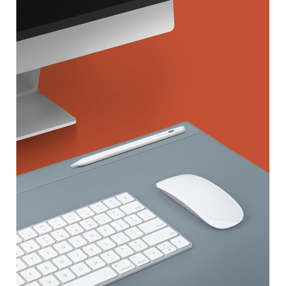 Una penna, una tastiera e un mouse bianchi su un tappetino grigio accanto a un monitor.