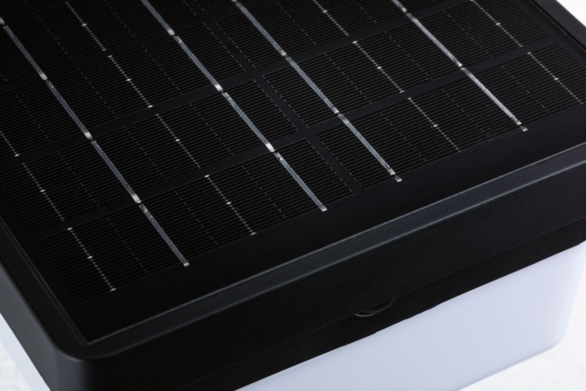 Nahaufnahme eines kleinen Solarmoduls mit schwarzem Rahmen auf einer weißen Basis.
