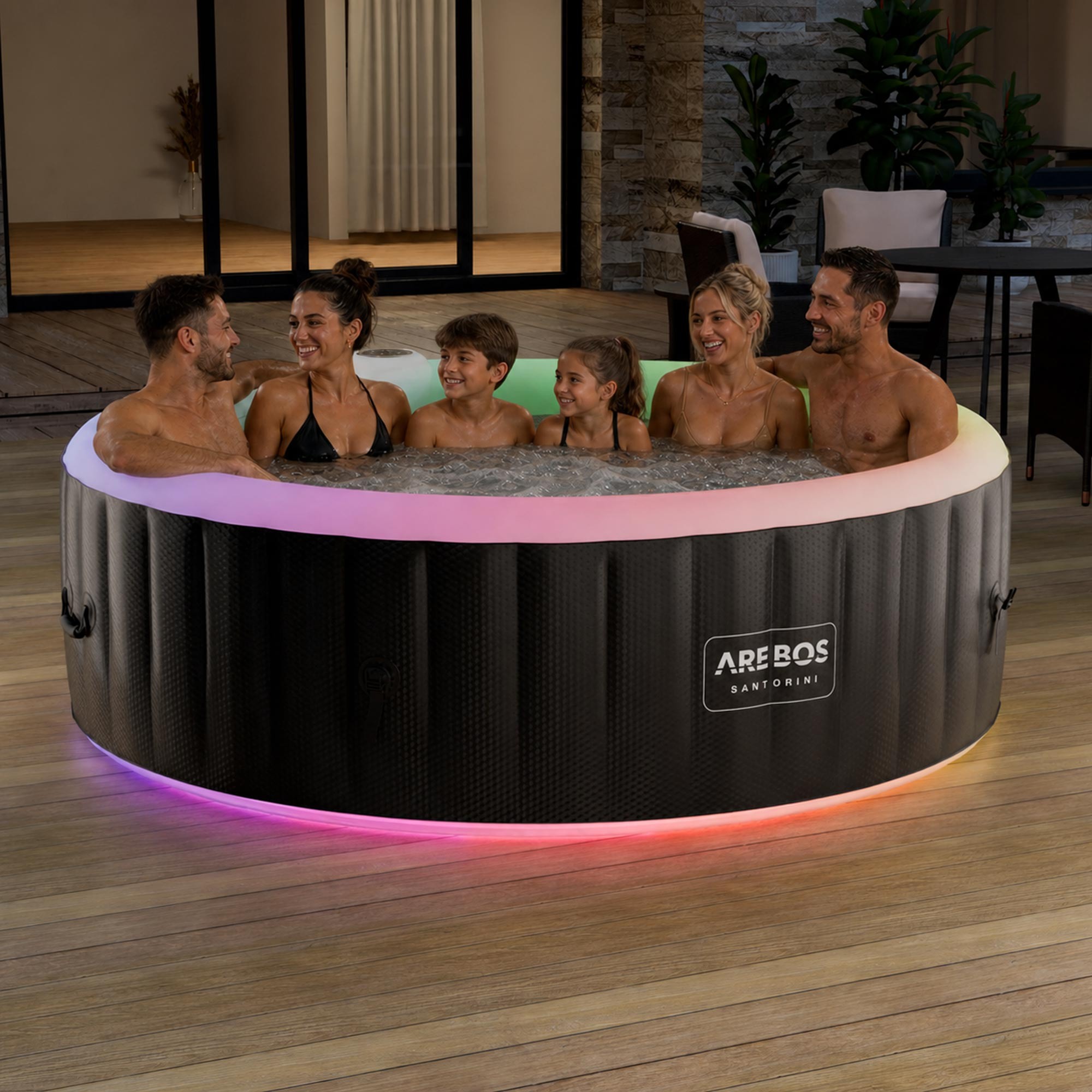 Eine Familie entspannt nachts in einem runden, beleuchteten Arebos Whirlpool auf einer Holzterrasse.