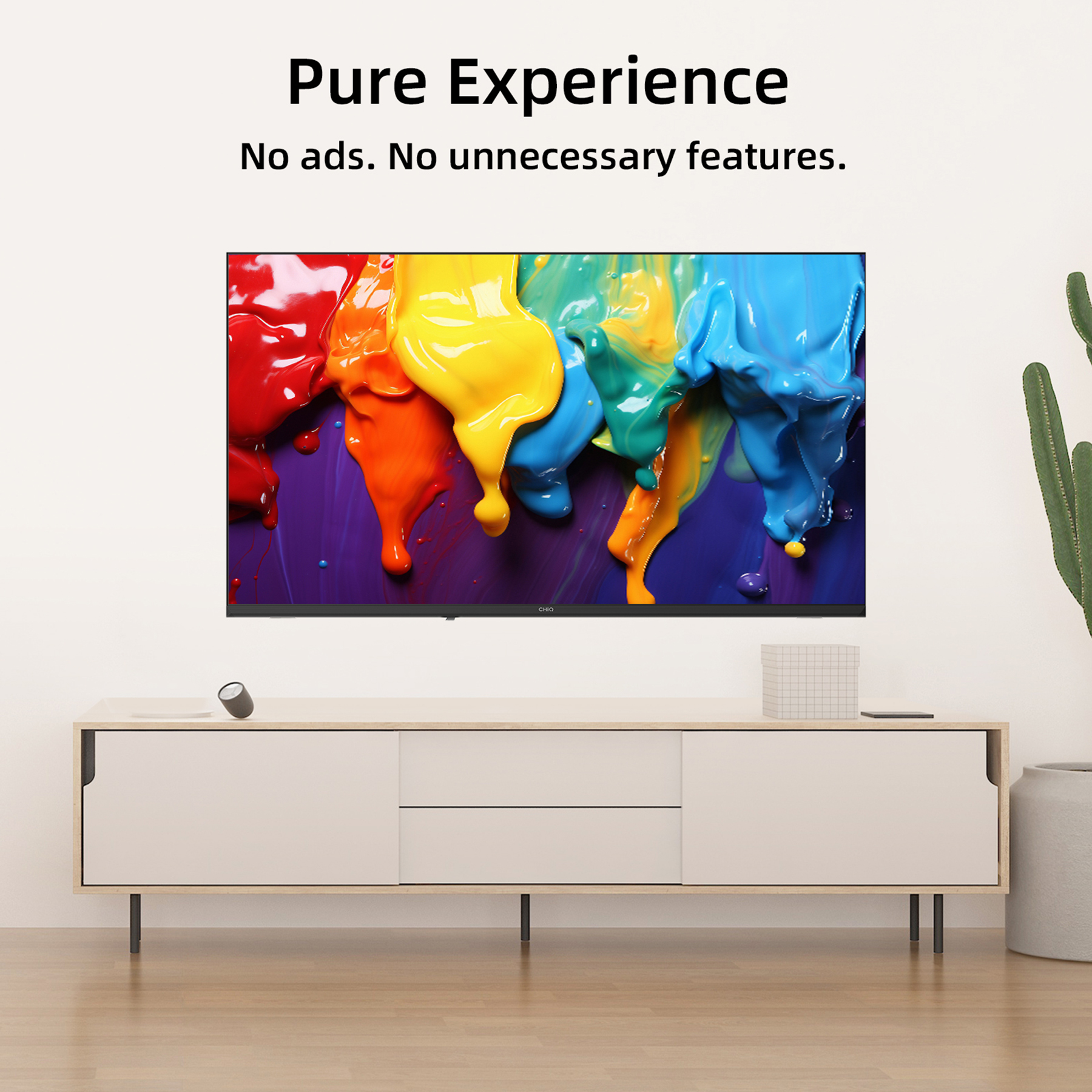 Un televisor con salpicaduras de pintura colorida se encuentra sobre un mueble blanco con un cactus a la derecha.