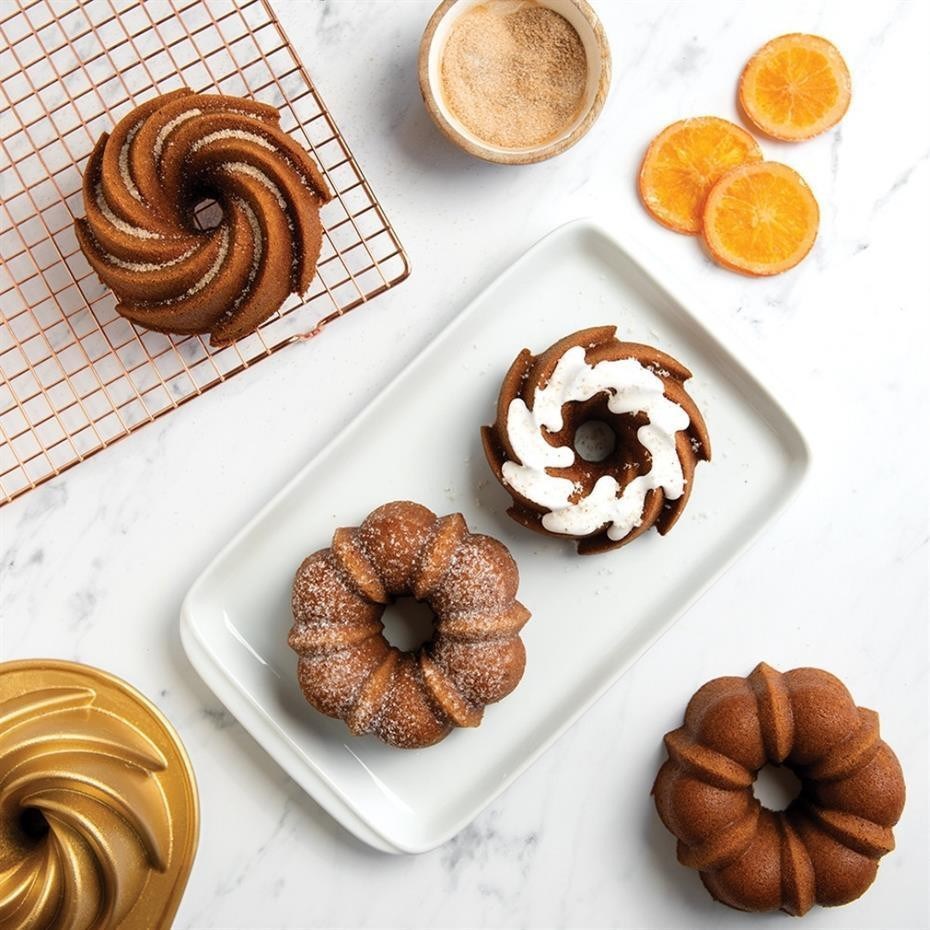 Beyaz mermer üzerinde mini bundt kekler, tabakta ve tel ızgarada, portakal dilimleri ve şekerle.