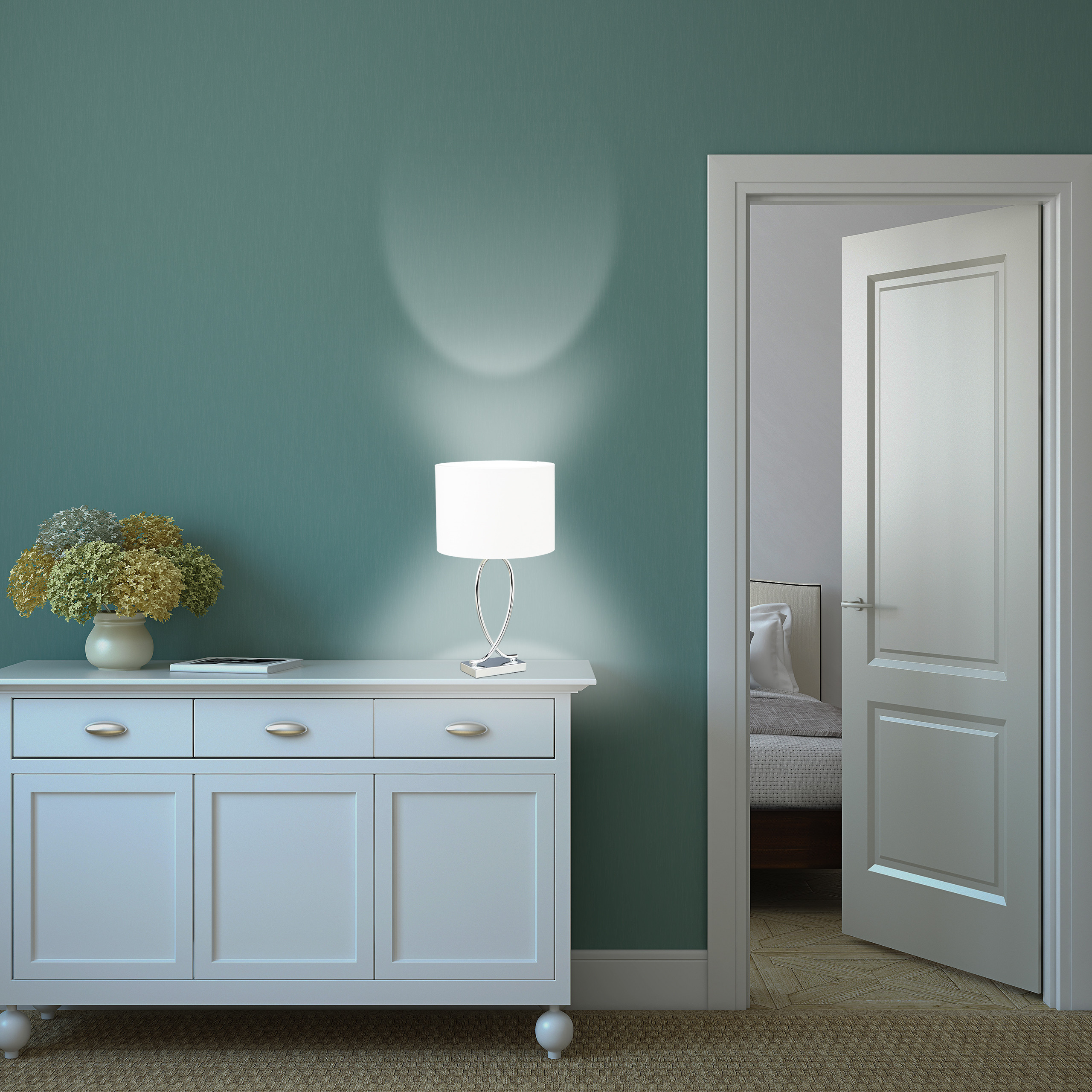 Eine weiße Kommode mit Lampe steht vor einer grünen Wand. Rechts führt eine offene Tür in ein Schlafzimmer.