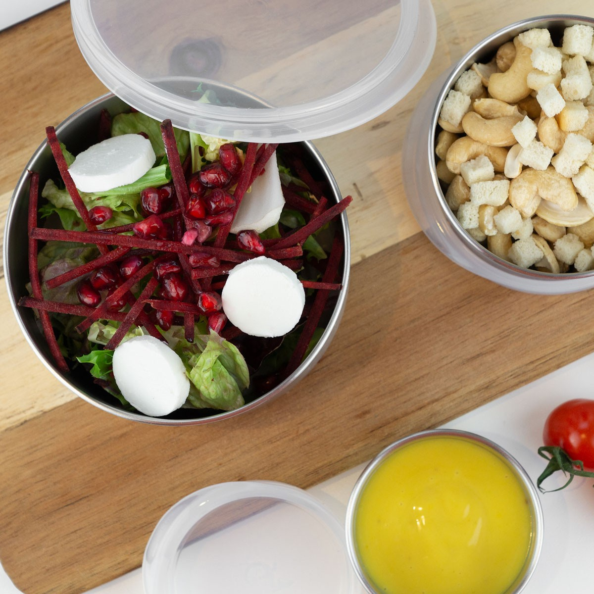 Contenitori in acciaio inox con insalata, noci e condimento.