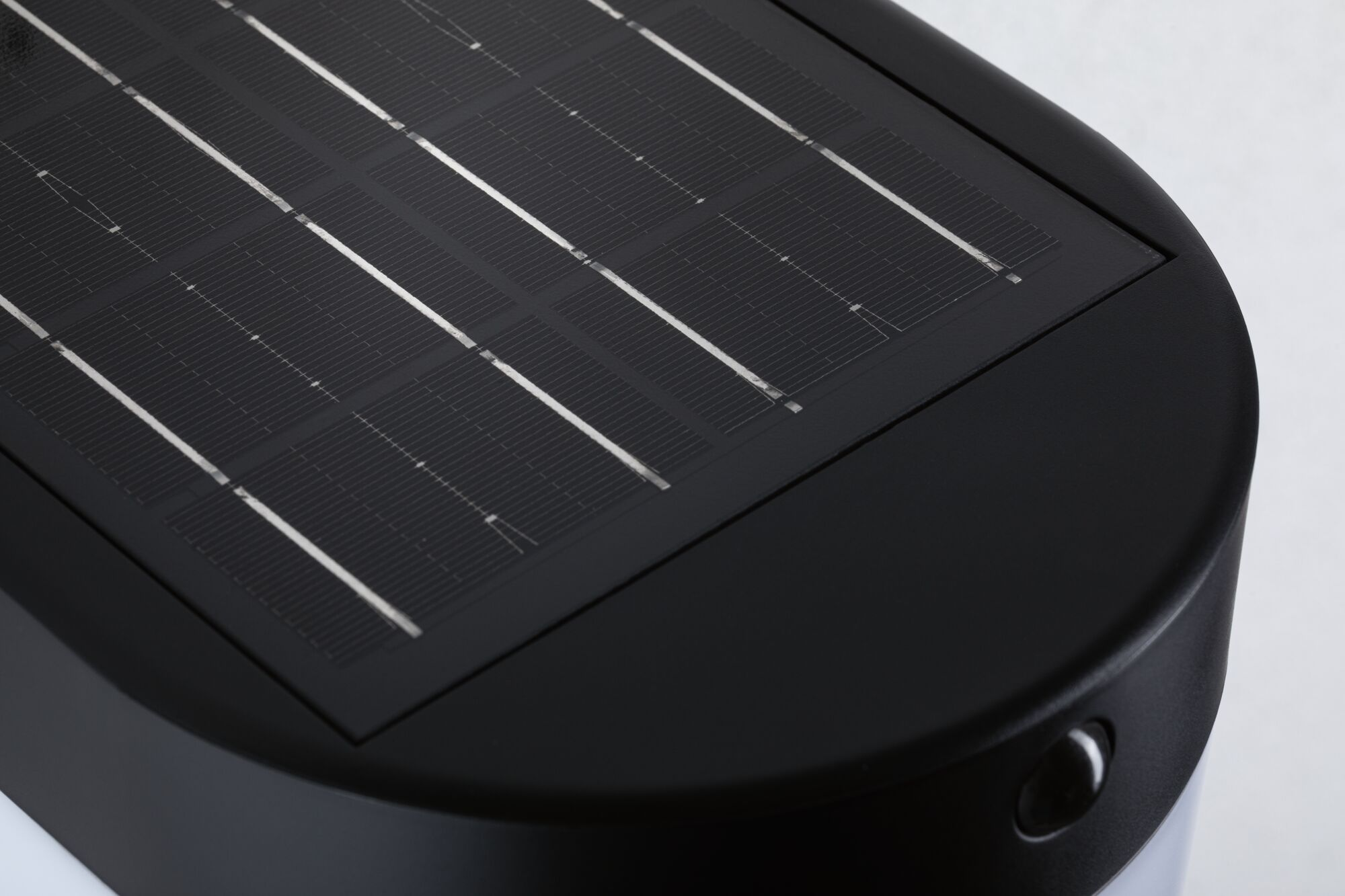 Ein kleines Solarpanel auf einer schwarzen, abgerundeten Vorrichtung vor weißem Hintergrund.