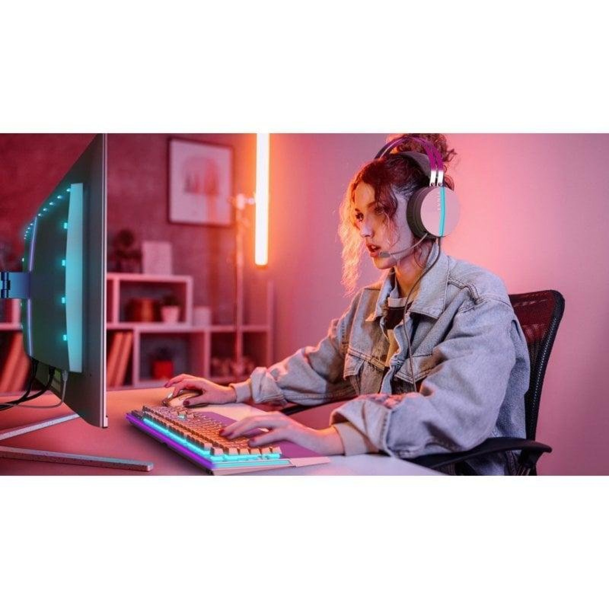 Eine junge Frau mit Headset spielt an einem bunt beleuchteten PC in einem Raum mit sanftem rosafarbenen Licht.