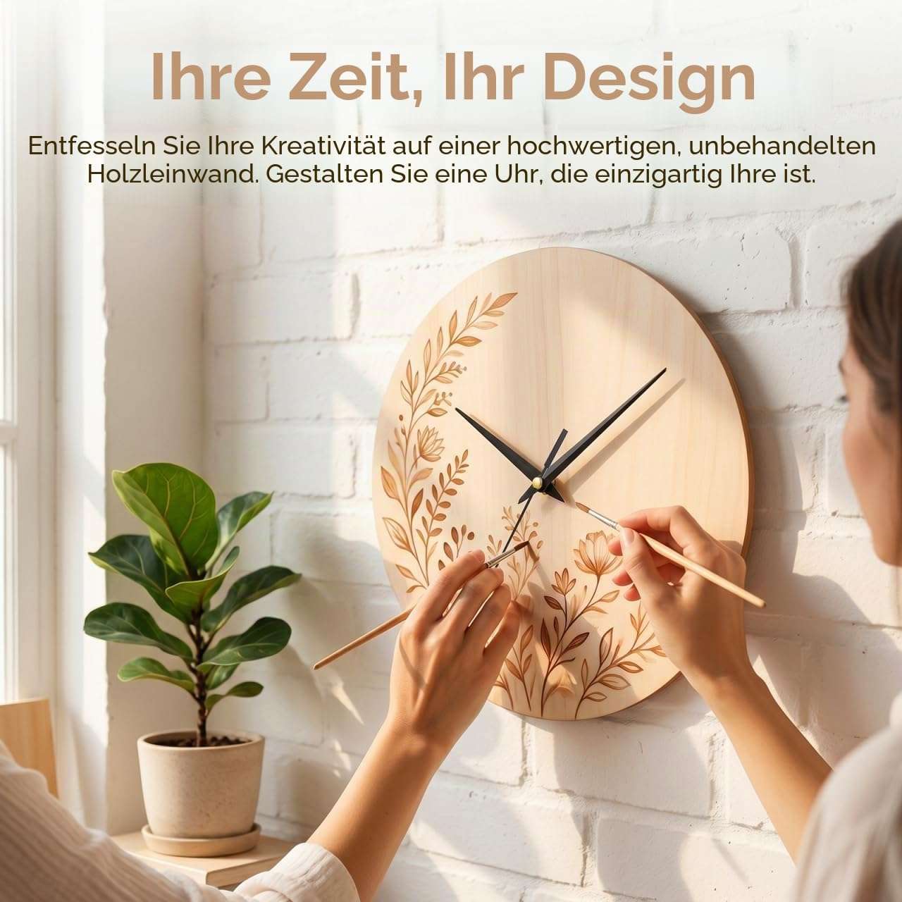 Eine Frau bemalt eine runde Holzleinwanduhr mit Blumenmotiven vor einer Backsteinwand.