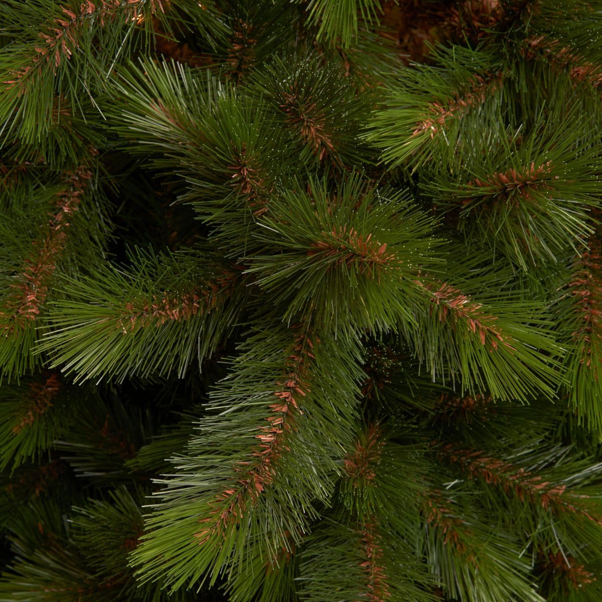 Gros plan de branches de pin artificiel vert denses avec des tiges brunes.