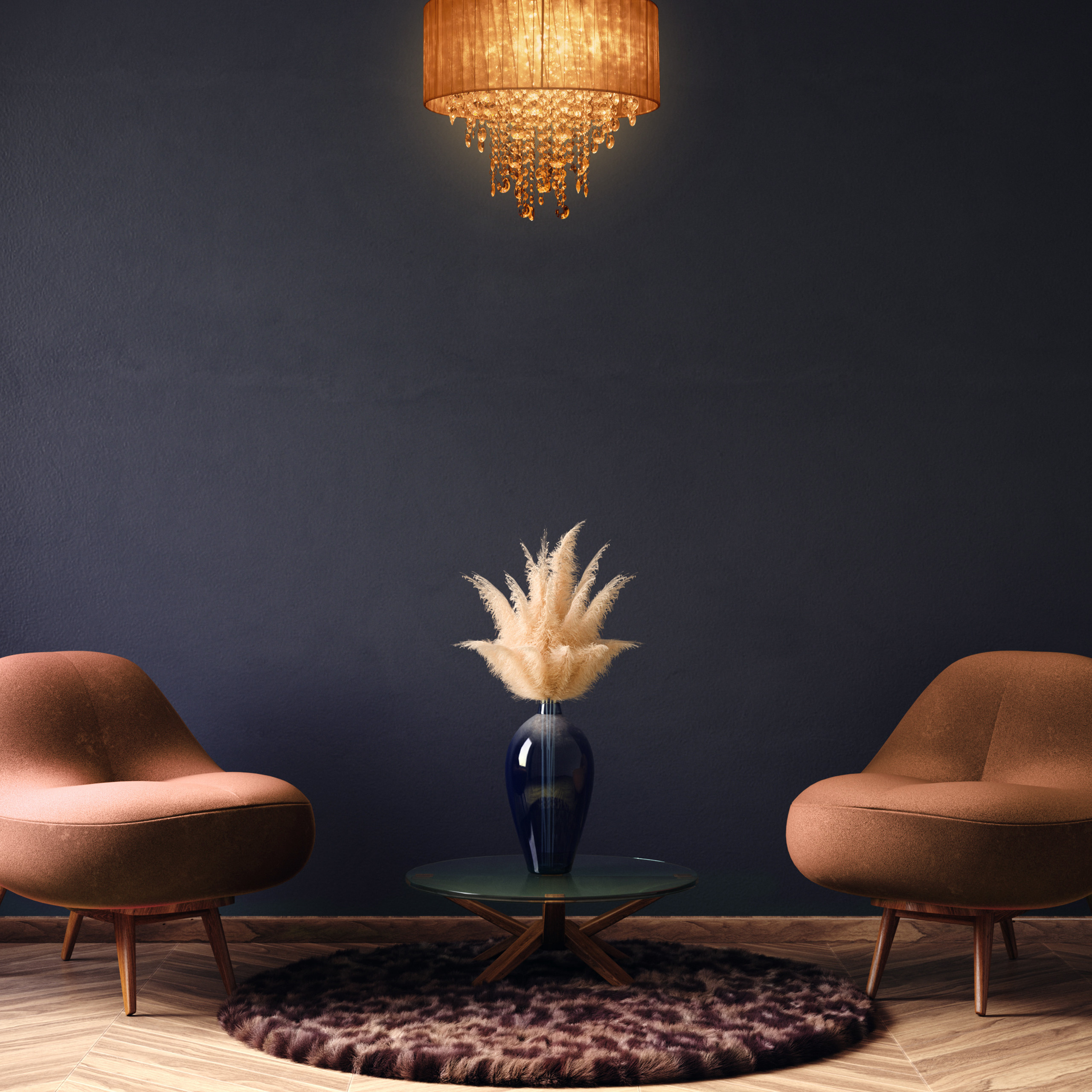 Zwei braune Sessel, ein Glas-Couchtisch mit Pampasgrasvase und ein Kronleuchter vor einer dunklen Wand.