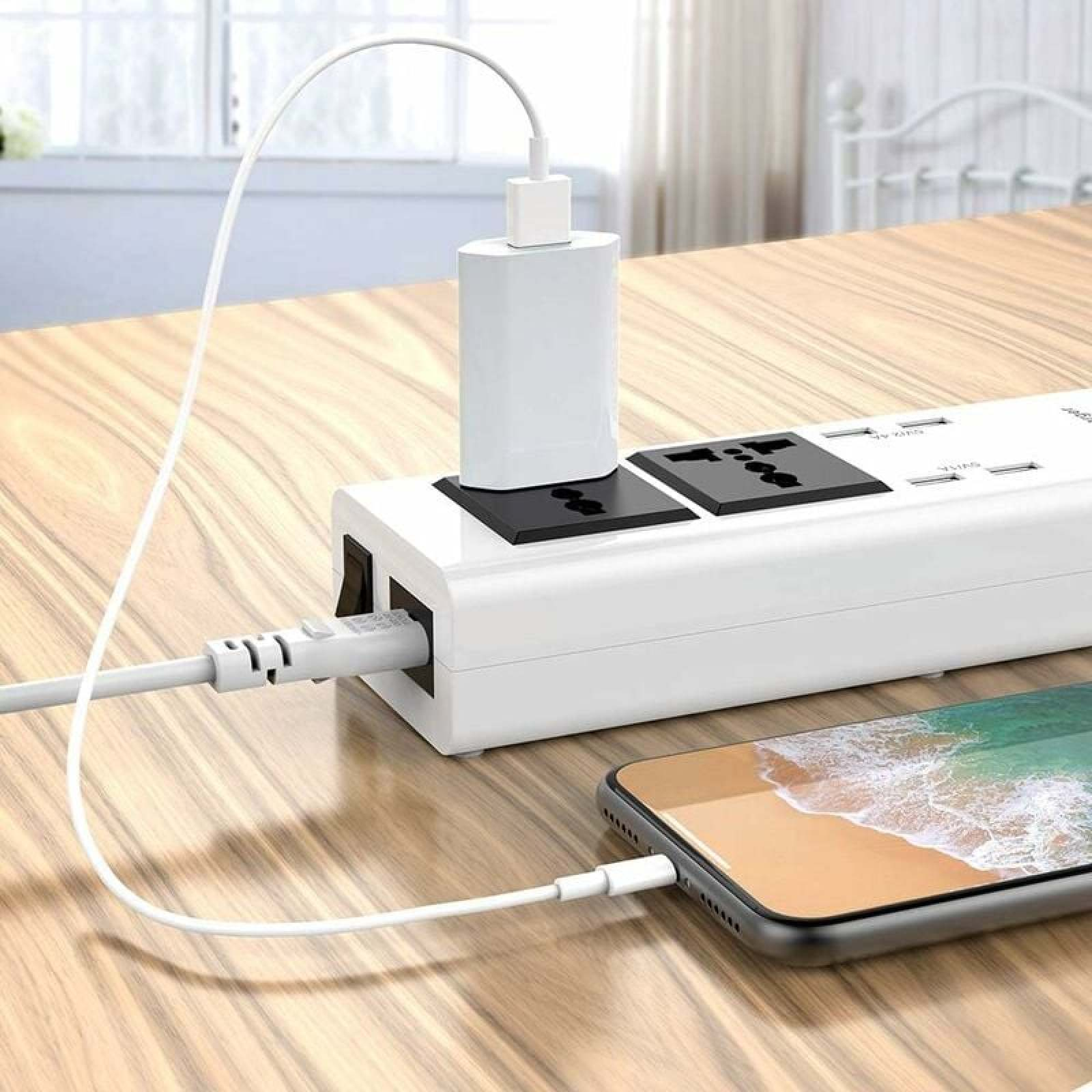 Eine weiße Steckdosenleiste auf einem Holztisch mit einem angeschlossenen Smartphone und Netzteil.