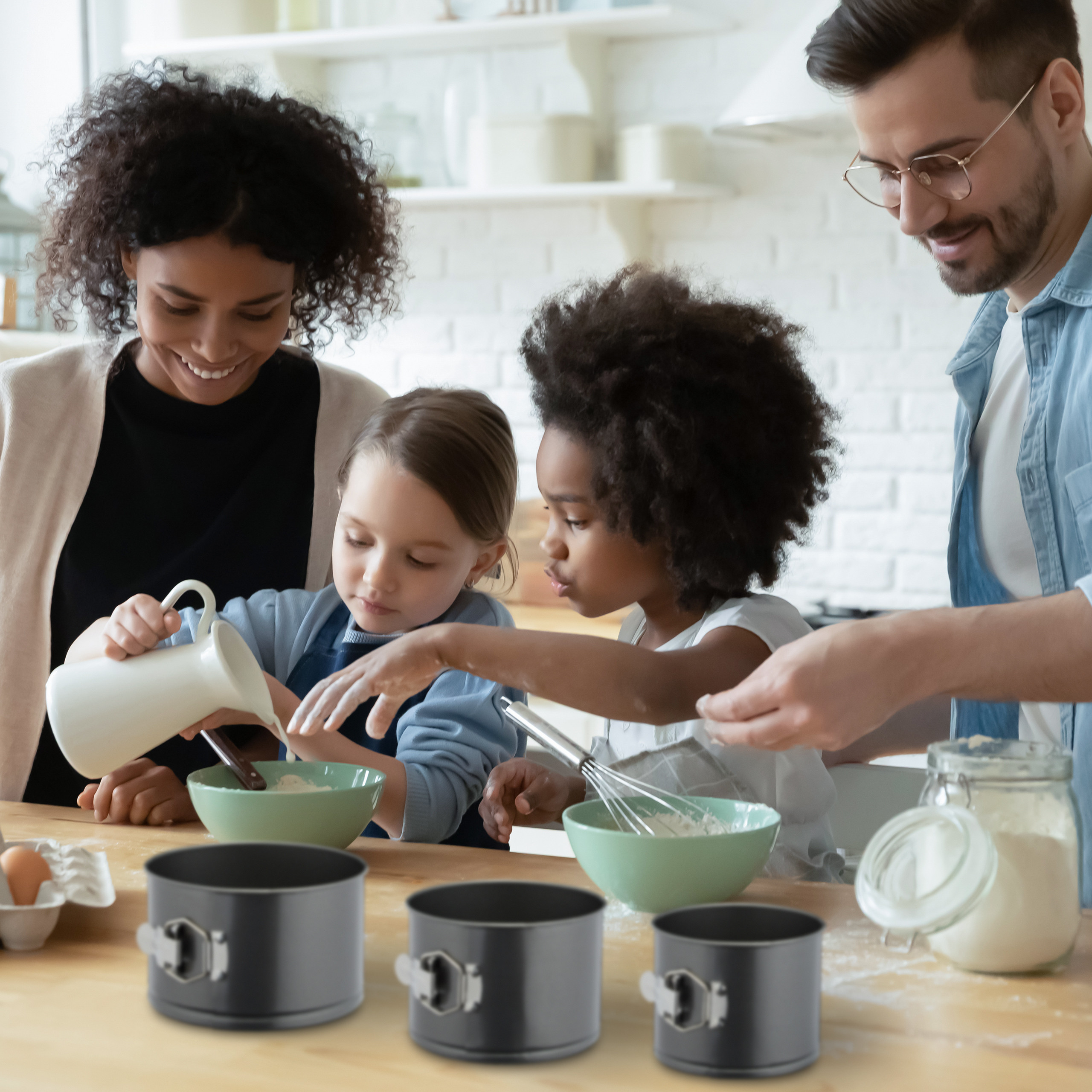 Eine diverse Familie backt zusammen in einer Küche und rührt Teig in Schüsseln an.