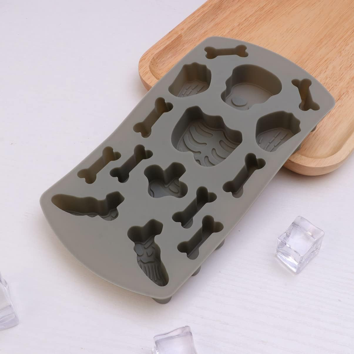 Graue Silikon-Eisform mit Knochen-, Schädel- und Skelettmotiven auf einem Holzbrett.