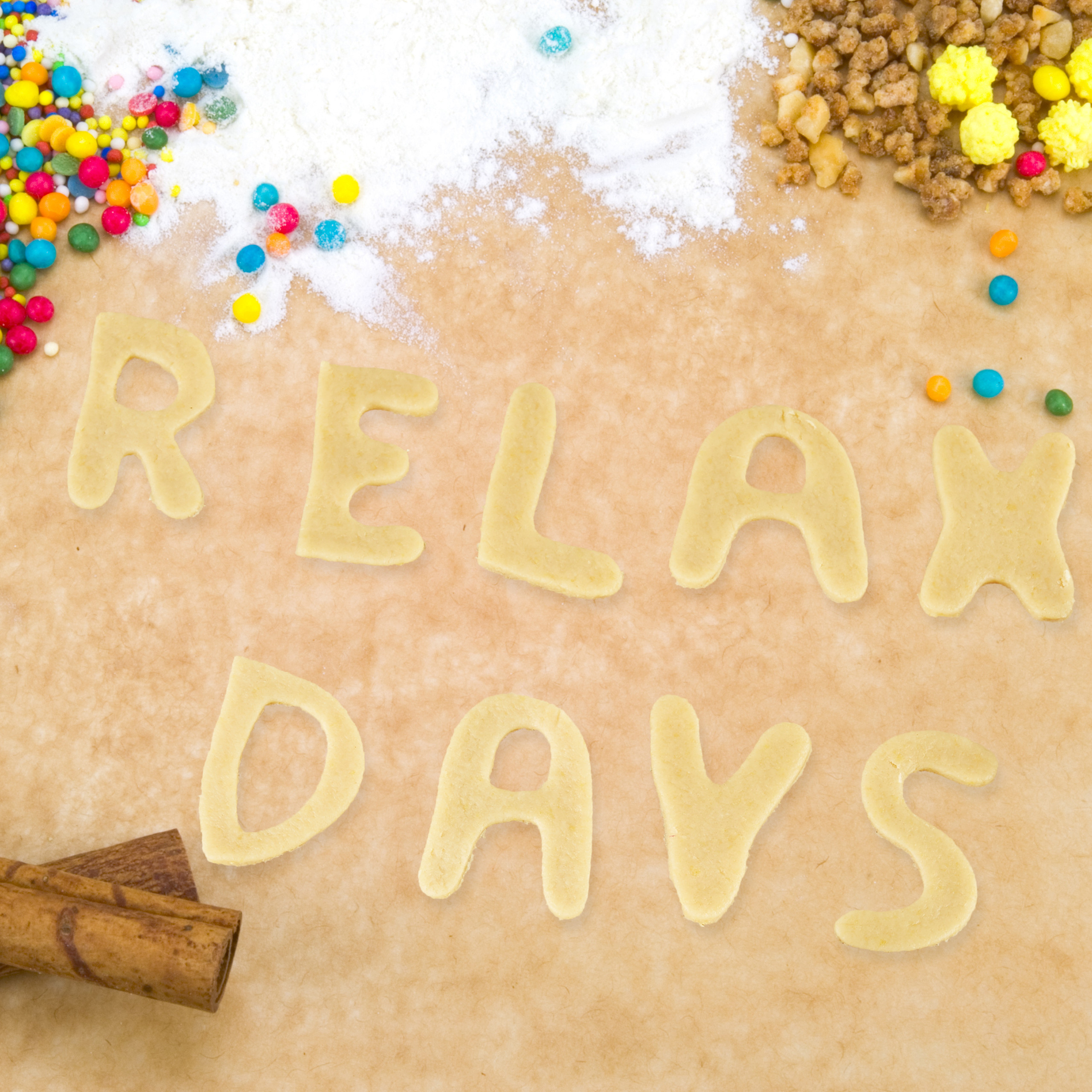 Keksstückchen formen den Schriftzug RELAX DAYS auf Backpapier mit Streuseln und Mehl.