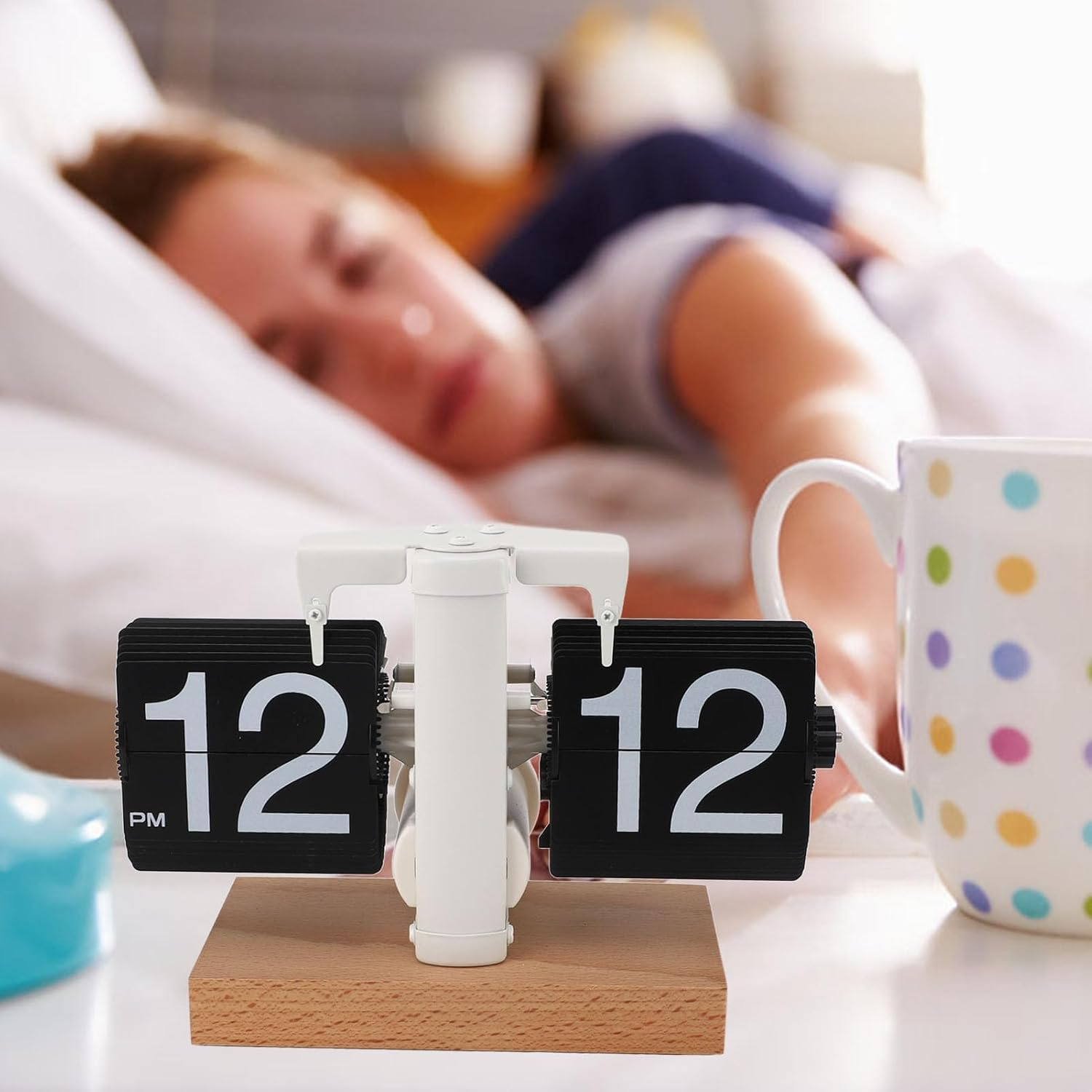 Ein wecker zeigt 12:12 pm im vordergrund, während eine frau im bett schläft.