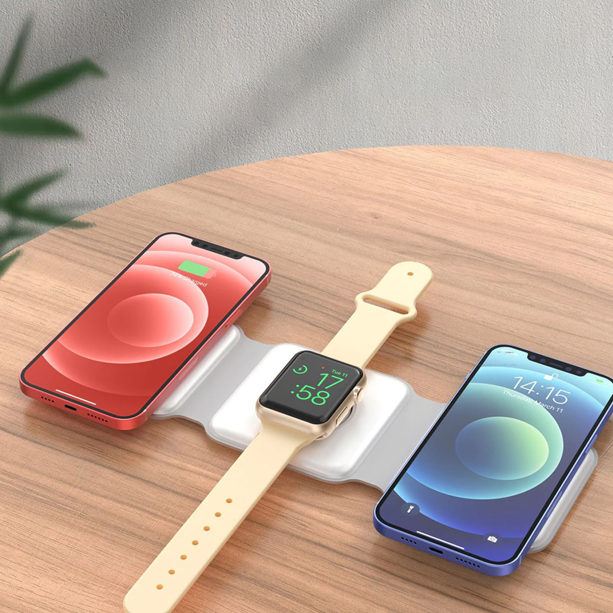 Ein rotes Smartphone, eine Smartwatch und ein blaues Smartphone laden auf einer kabellosen Ladestation.