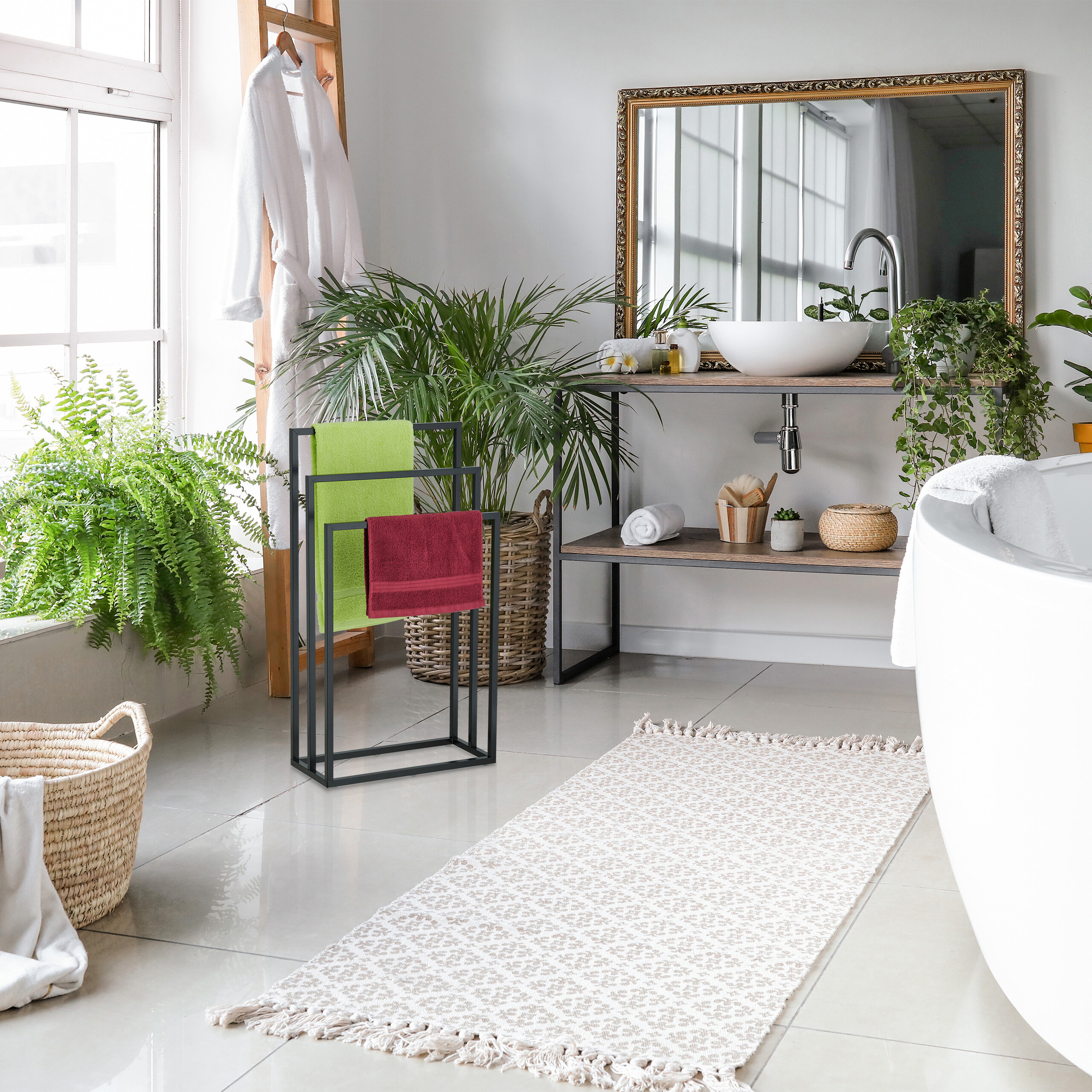 Ein helles Badezimmer mit Badewanne, Waschbecken, Spiegel, Handtuchhalter, Pflanzen und einem Teppich.