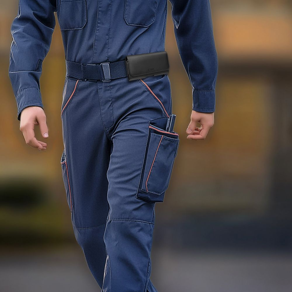 Ein Arbeiter in blauer Arbeitskleidung mit Gürtel und schwarzer Tasche geht durch den Raum.